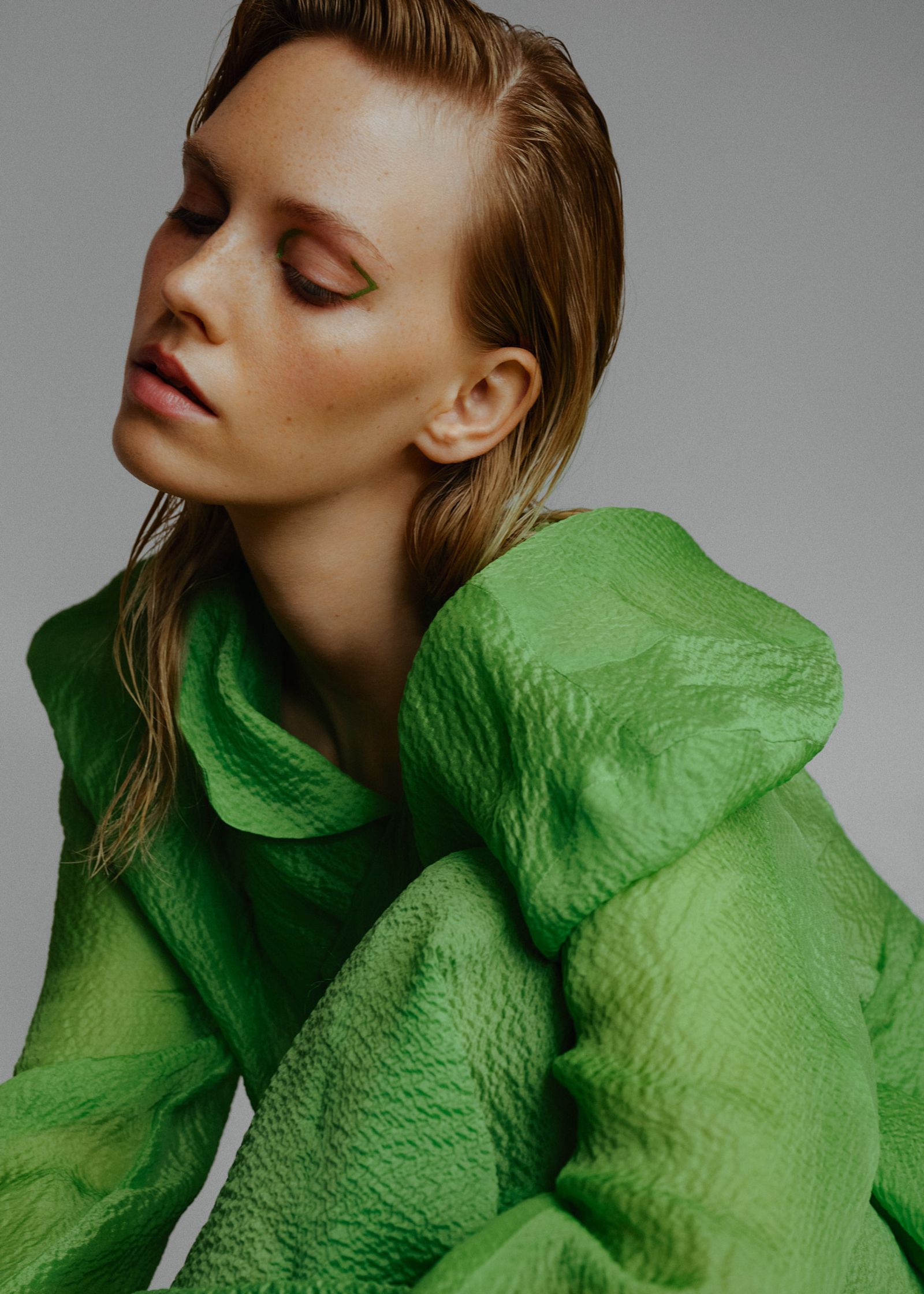 a woman in a green dress is posing for a magazine