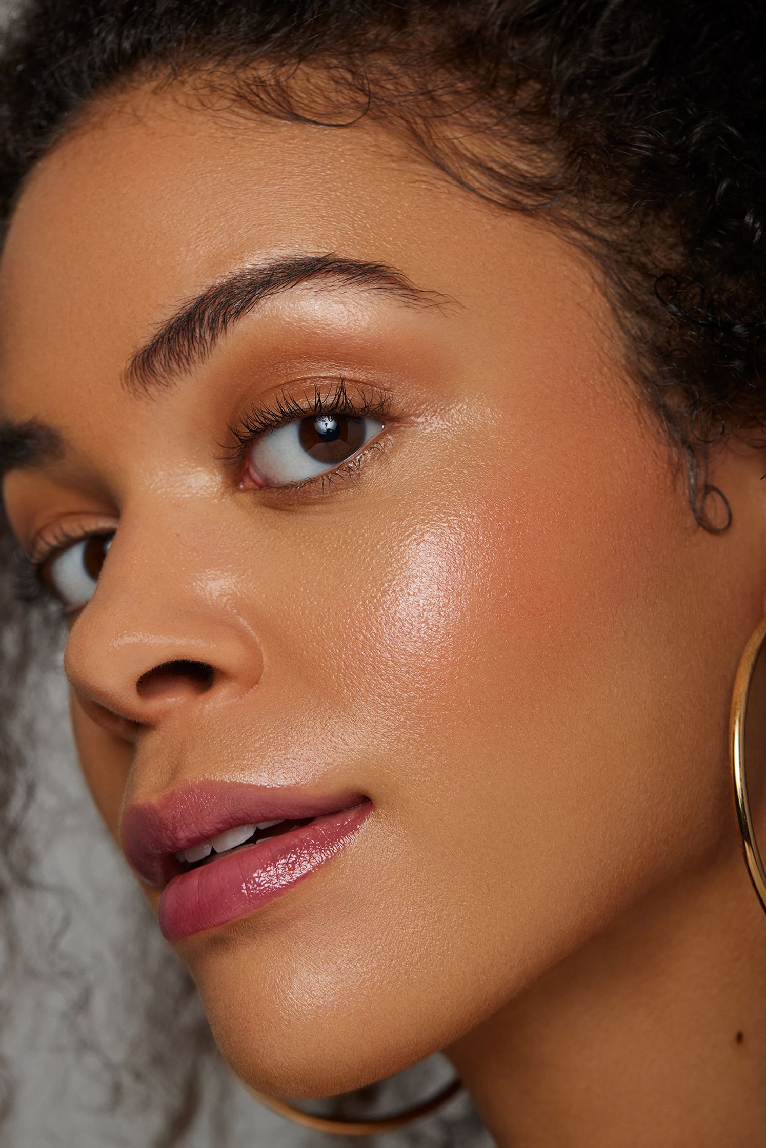 a woman with curly hair and gold hoop earrings