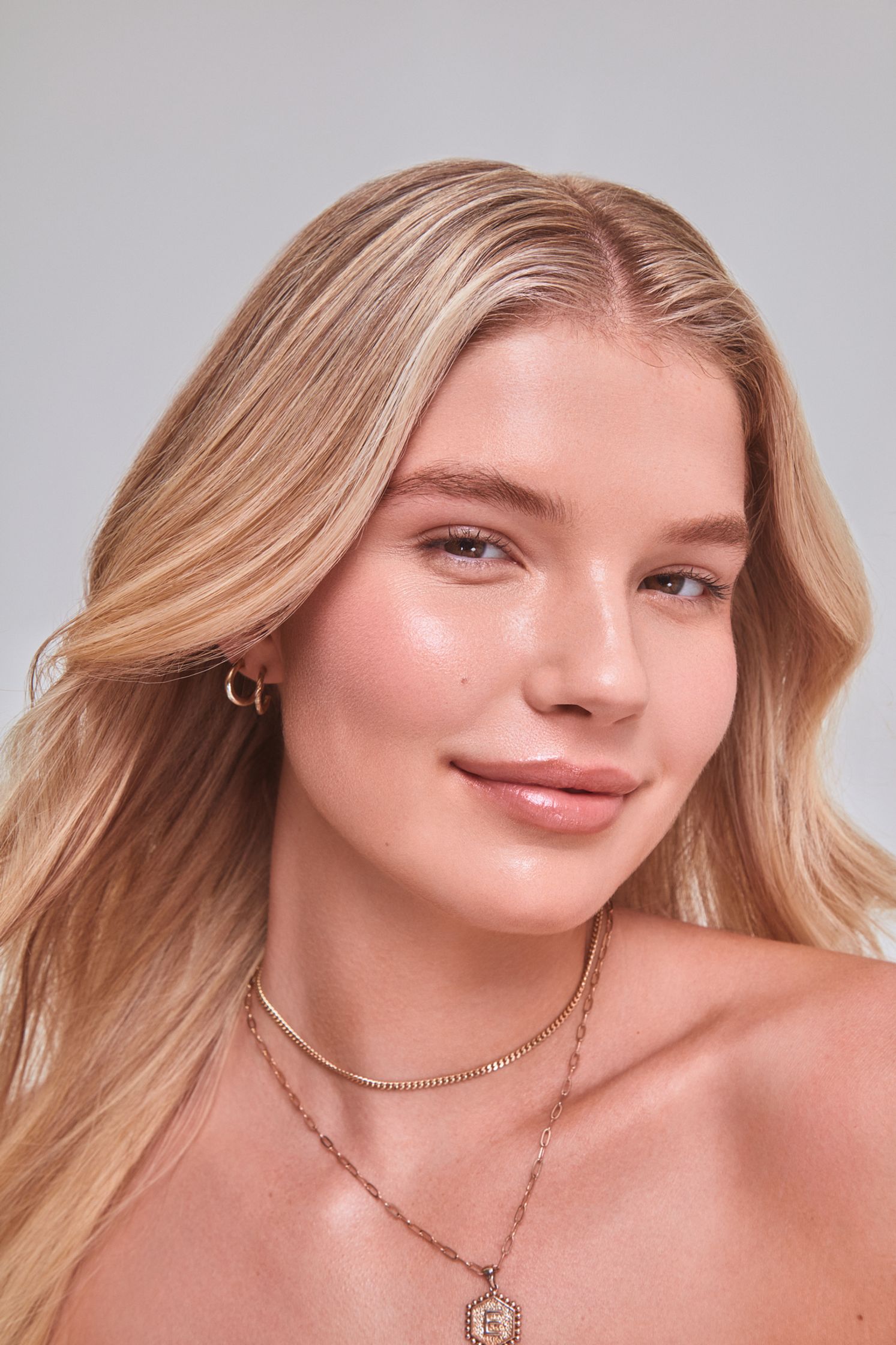 a woman with long blonde hair and a gold necklace posing for a photo