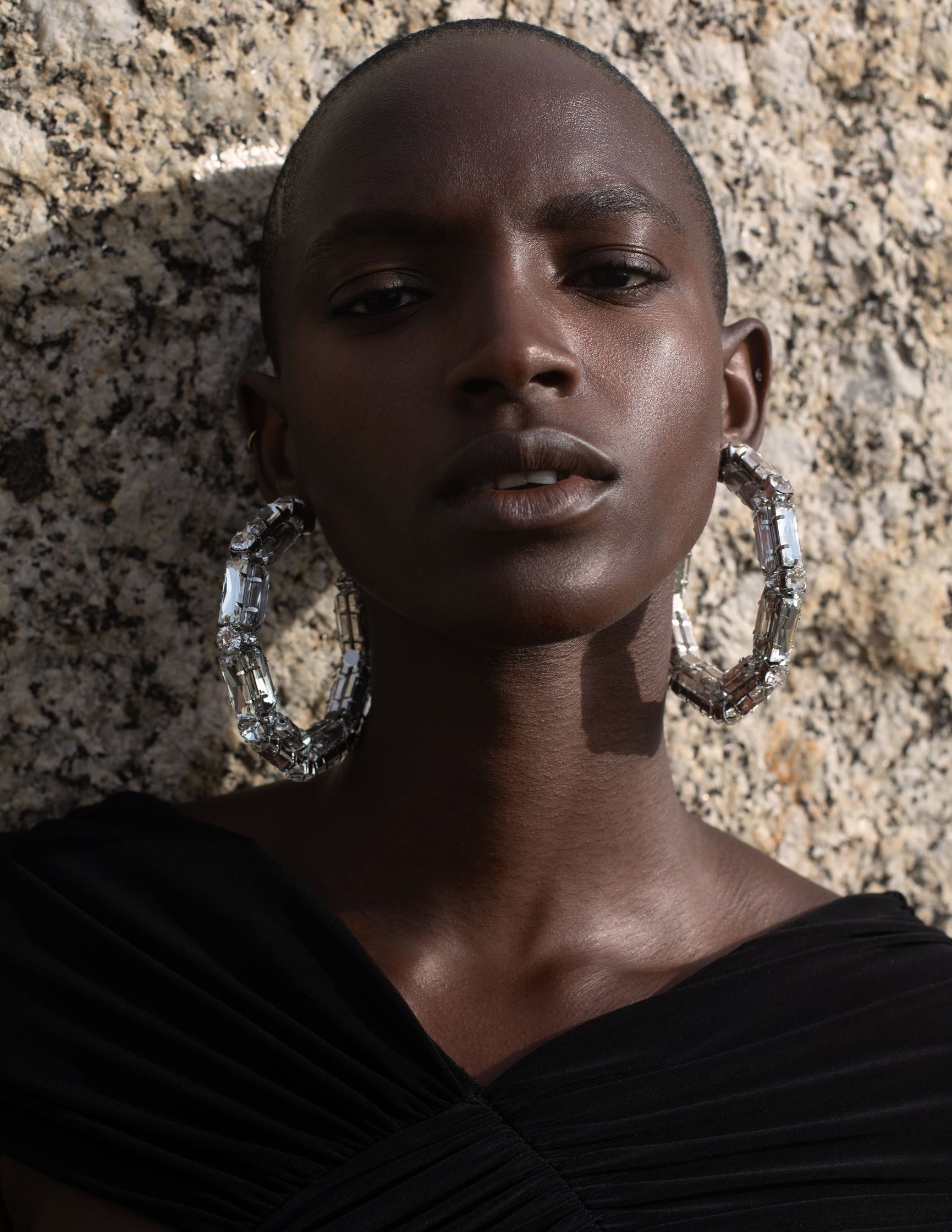 a black woman wearing a black dress and silver hoop earrings