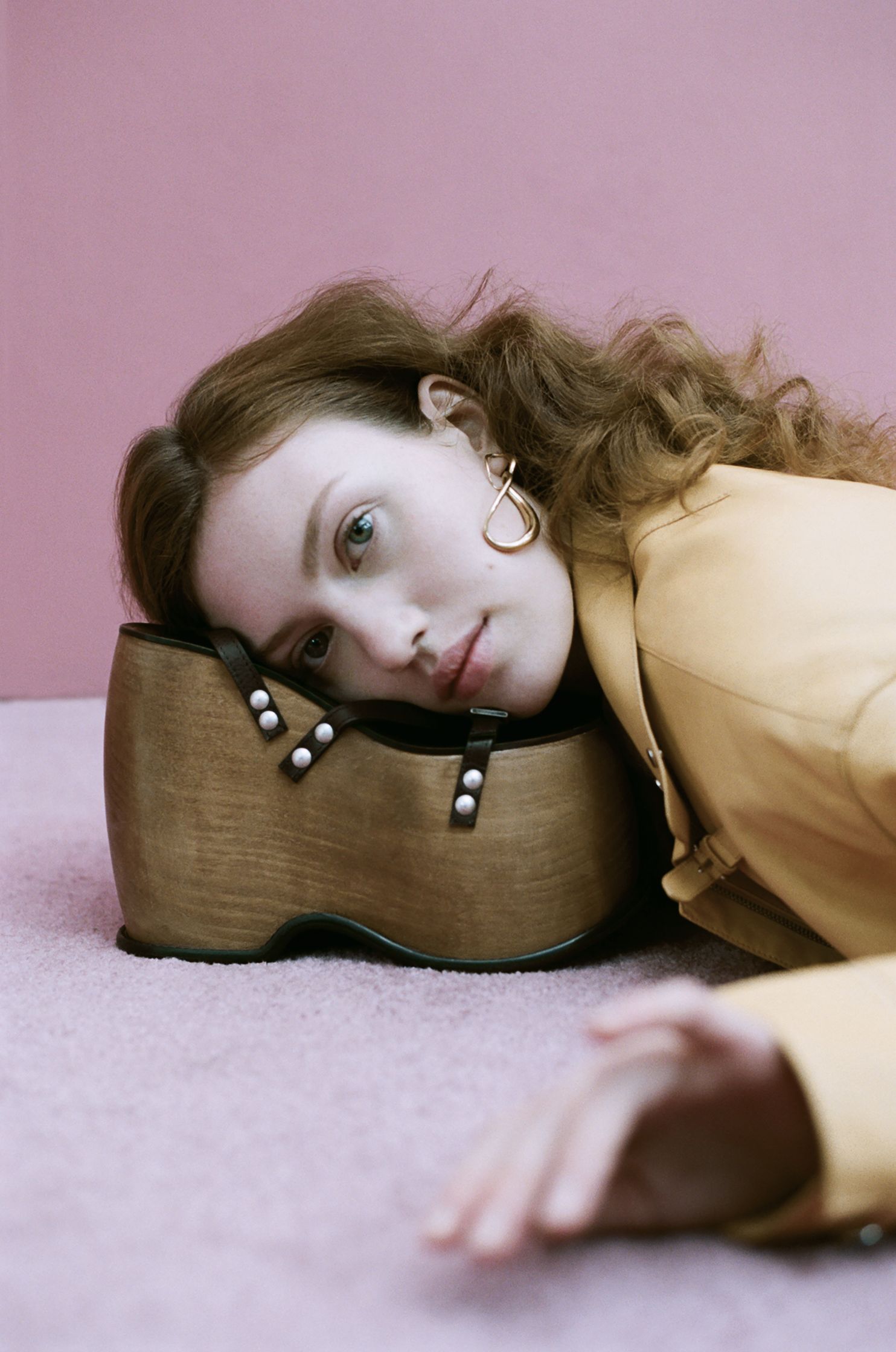 a woman laying on a pink carpet with a wooden shoe