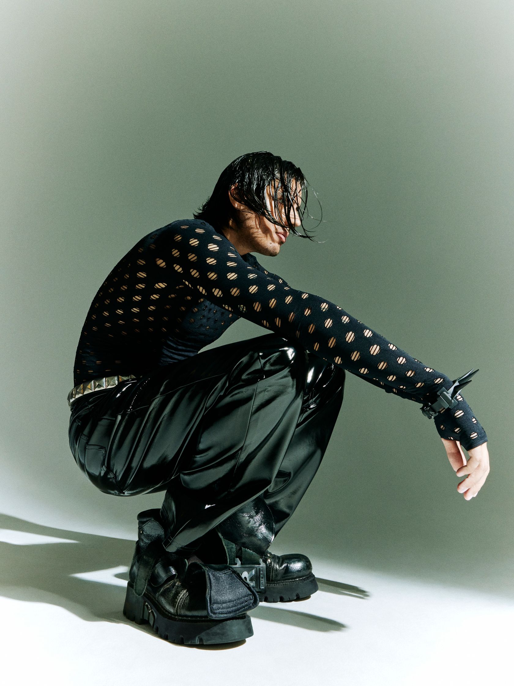 a man crouching down in black pants and a polka dot shirt