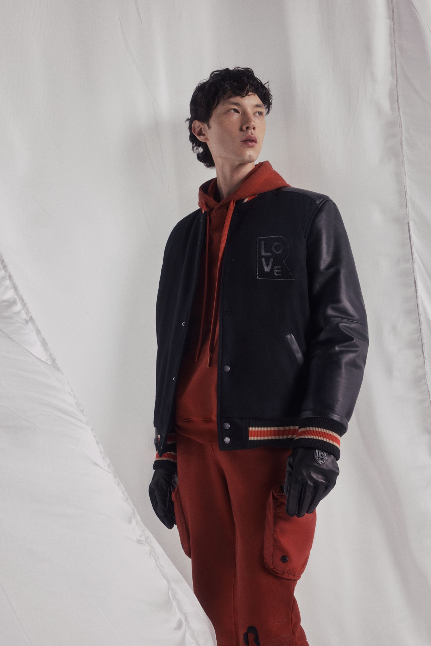 a model wearing a black jacket and red pants