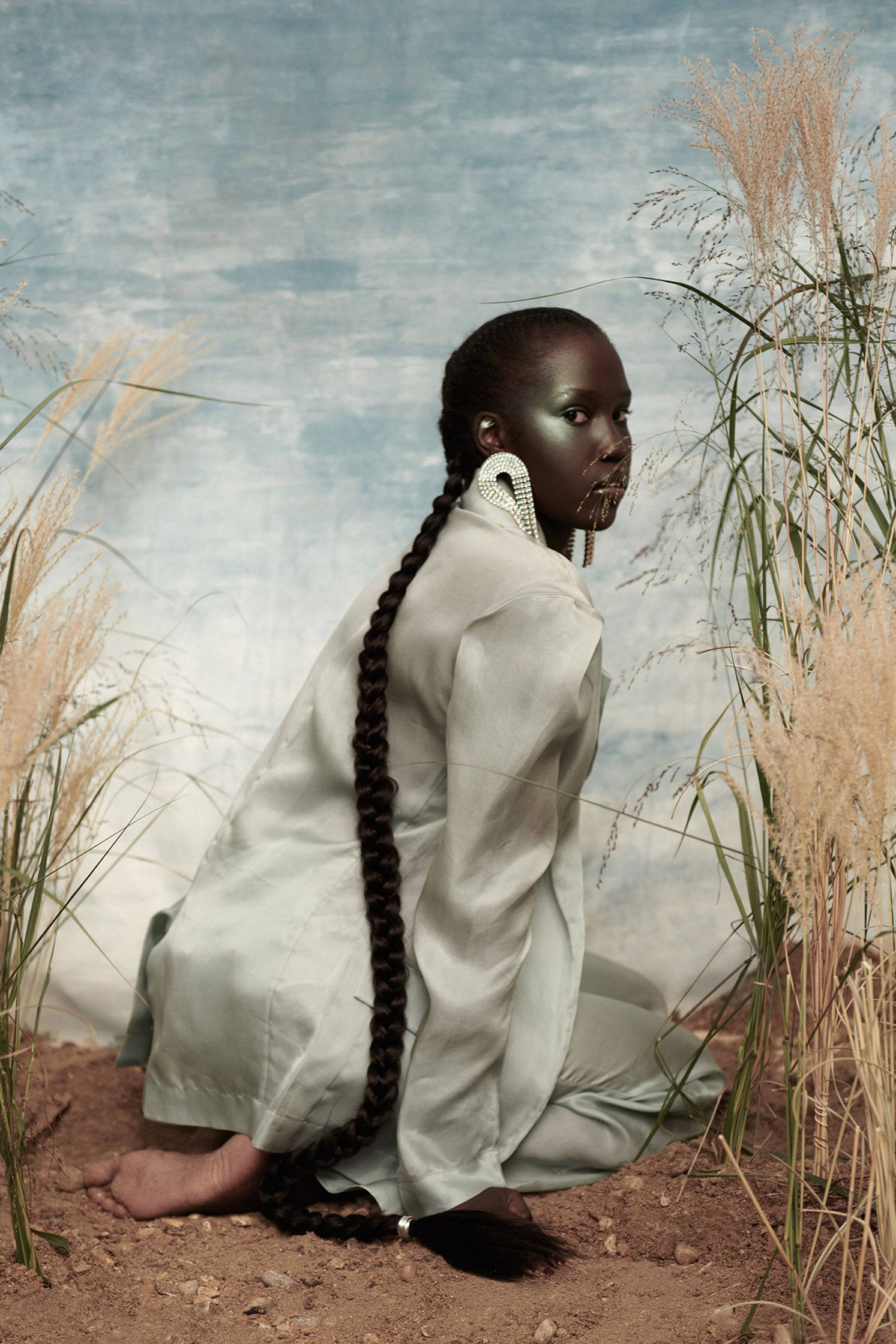 a woman sitting in the sand with long hair