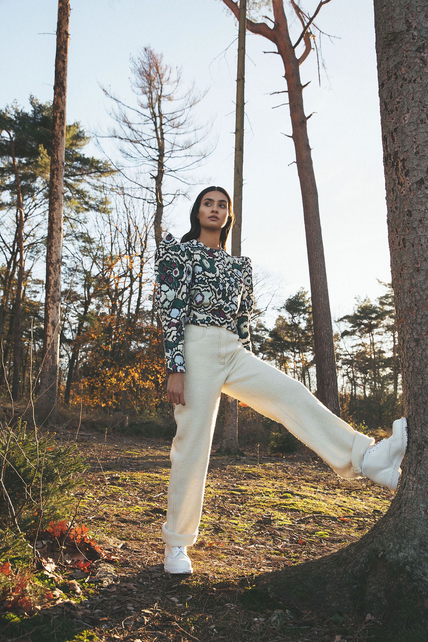 a woman leaning against a tree in the woods