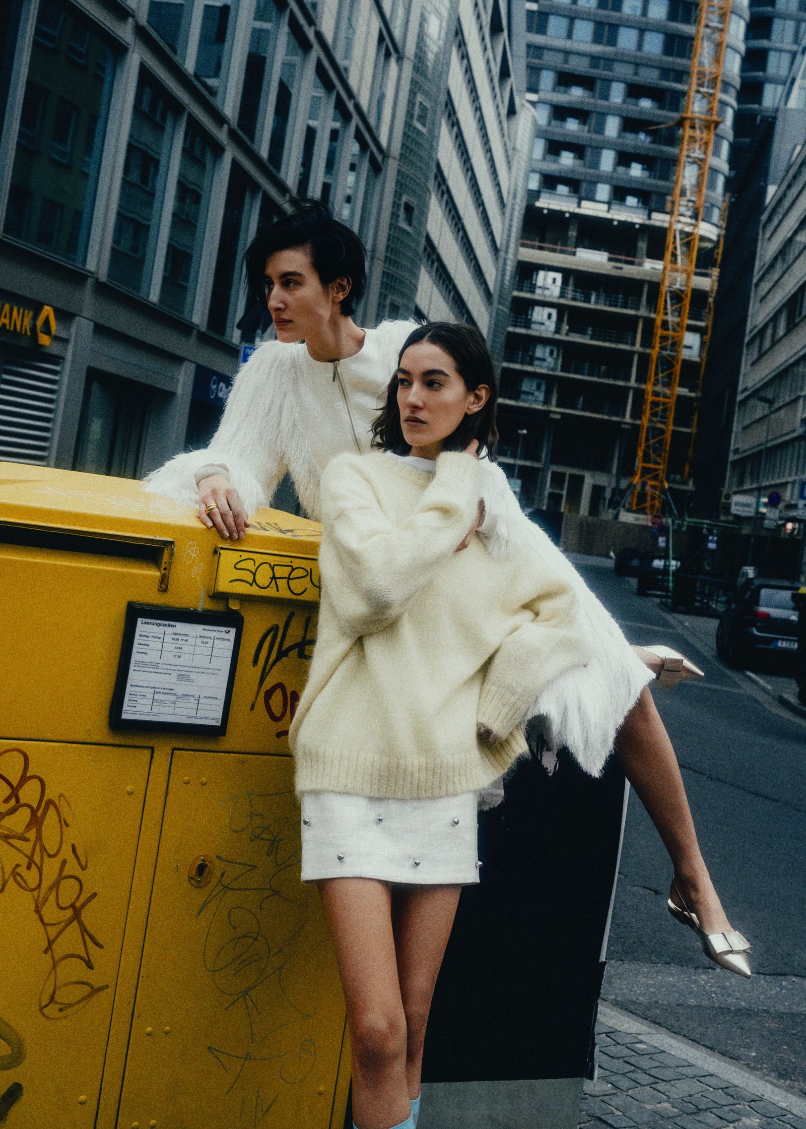 two women posing in front of a yellow box