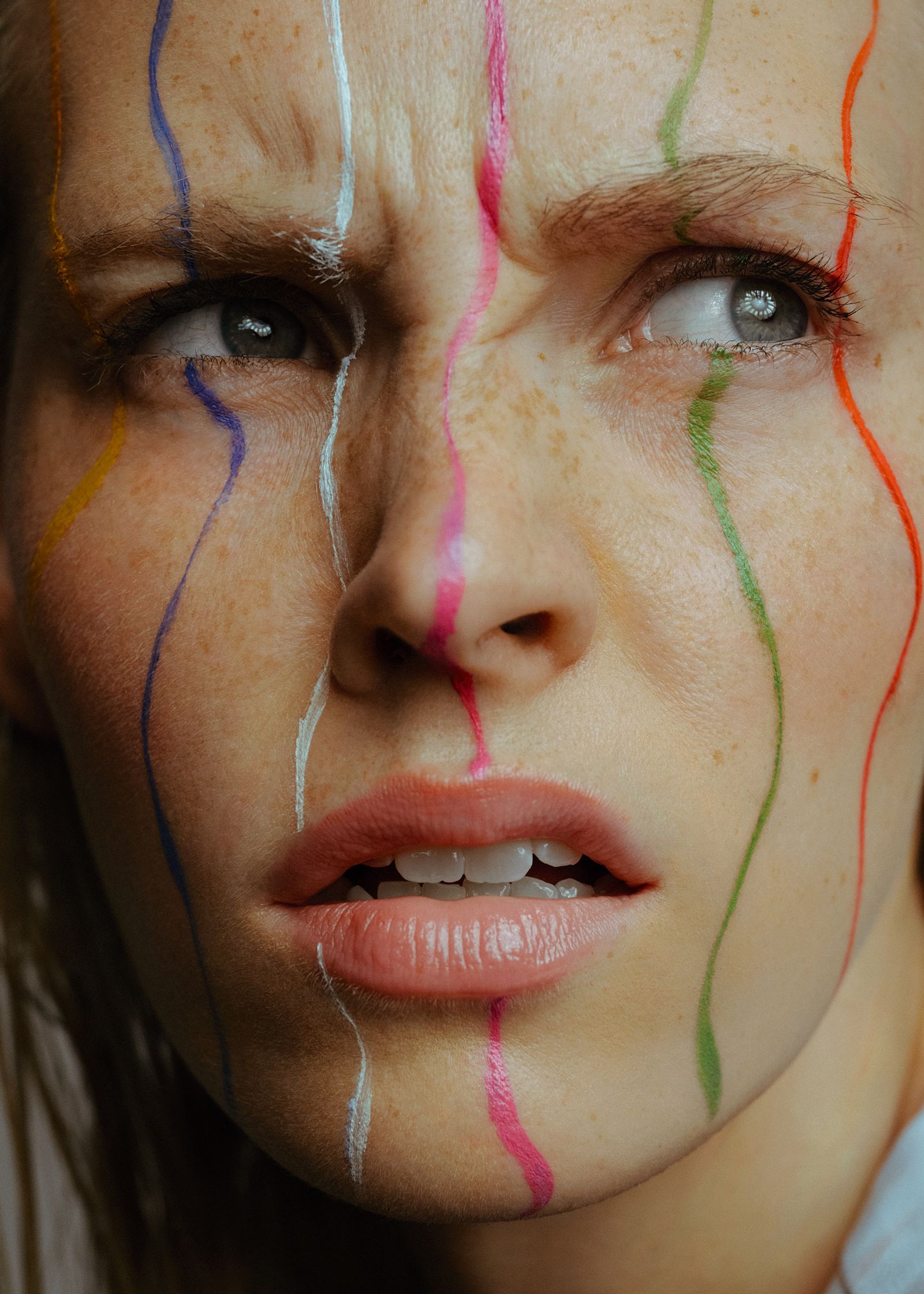 a woman with her face painted with colorful lines