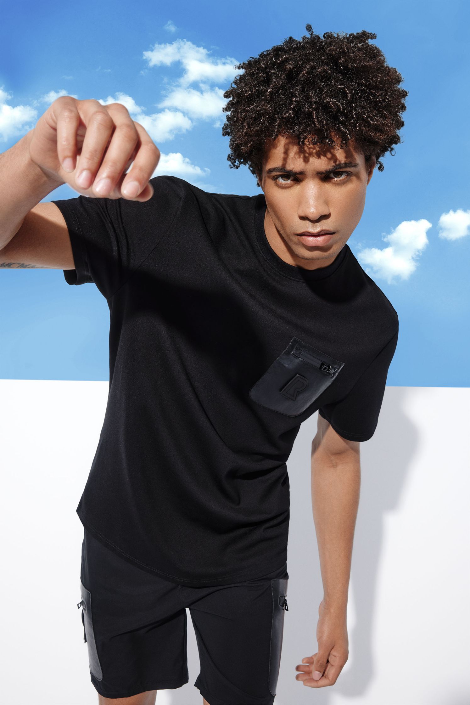 a young man wearing a black t - shirt and shorts