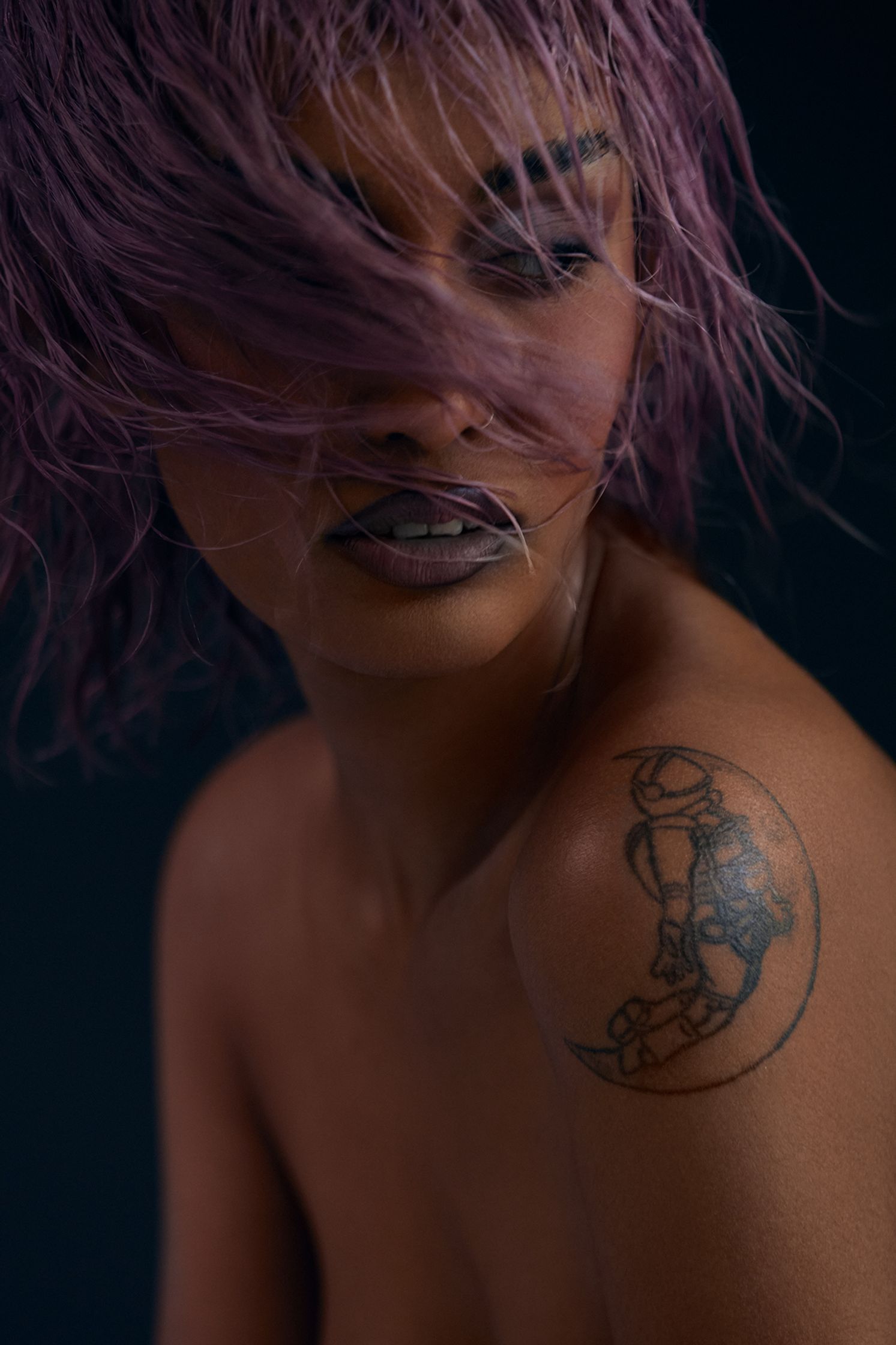 a woman with purple hair and a tattoo on her arm