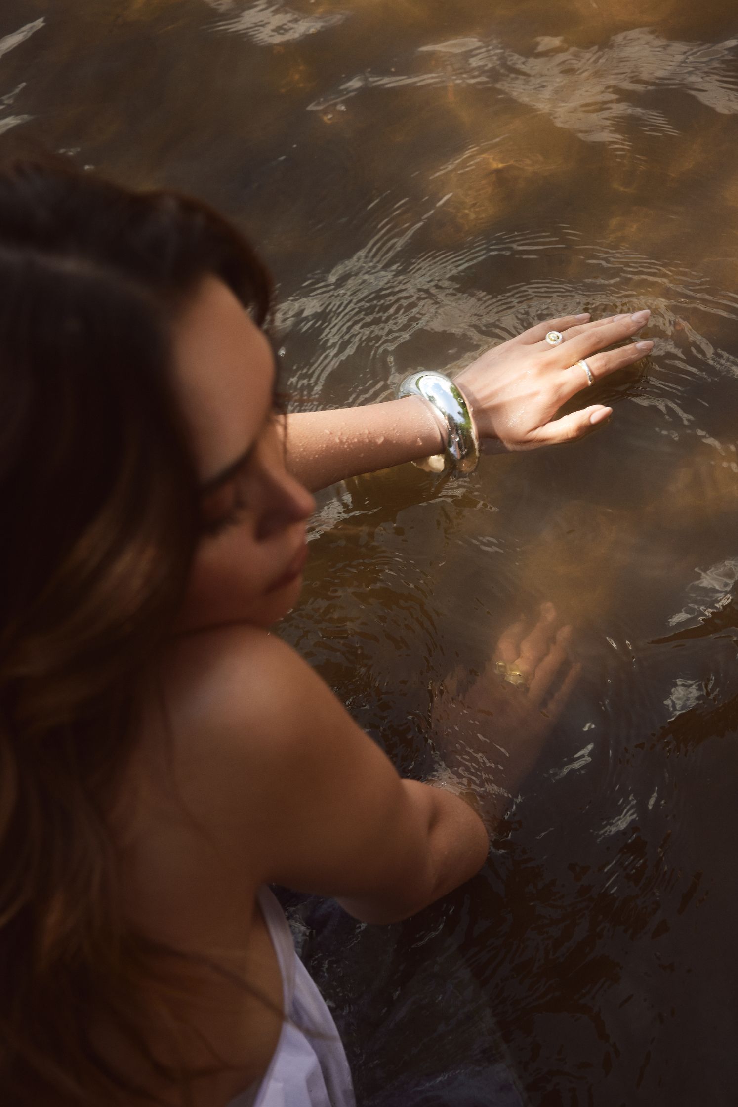 a woman is standing in the water with her hands in the water