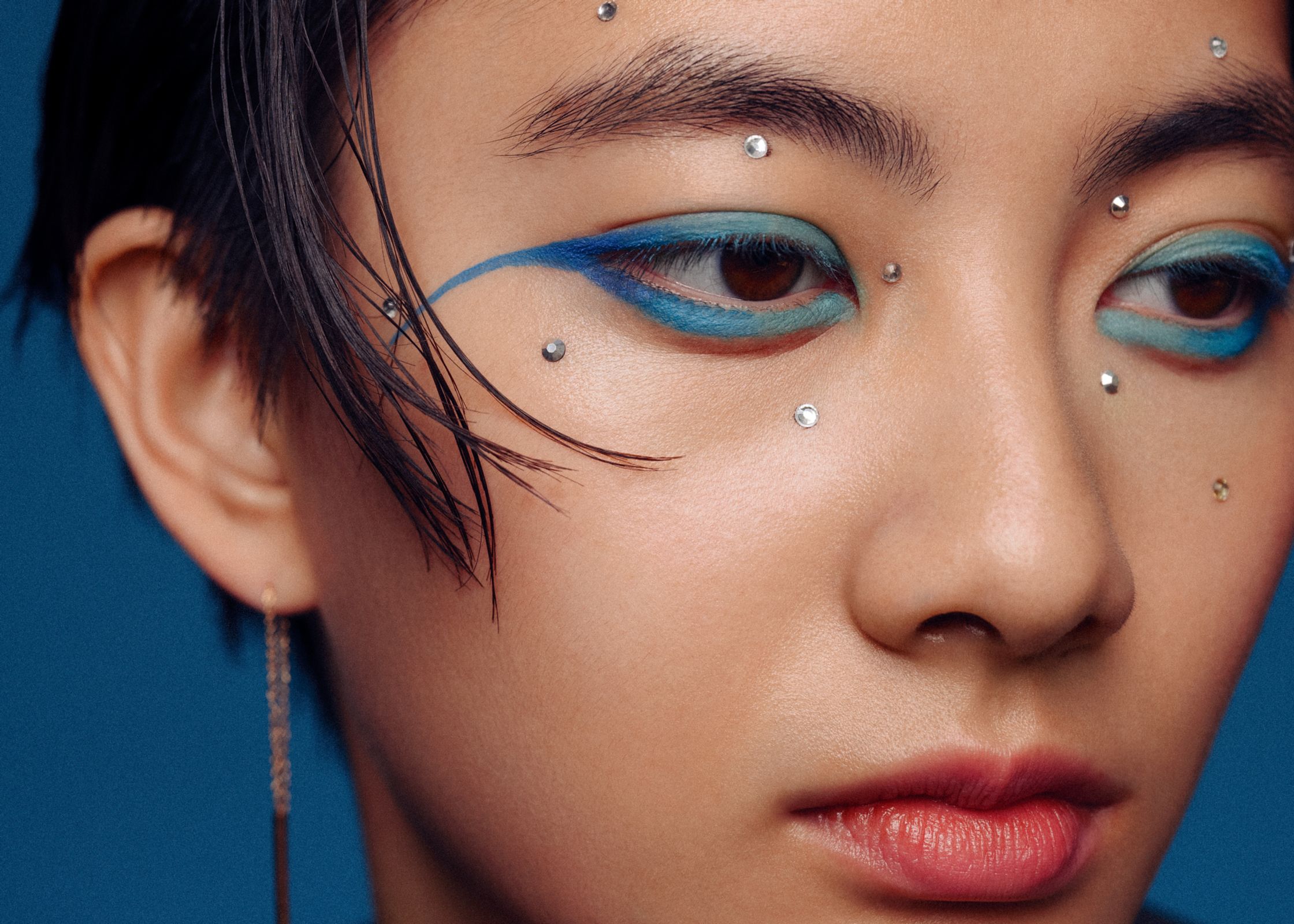 a woman with blue eye makeup and piercings