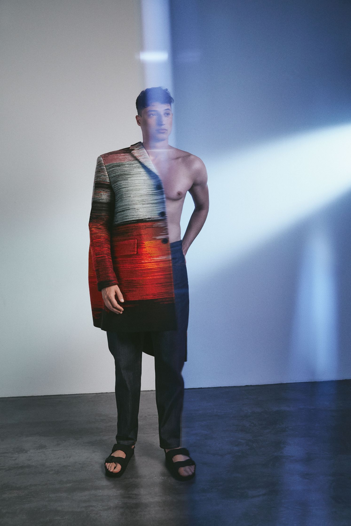 a man in a colorful jacket standing in front of a light