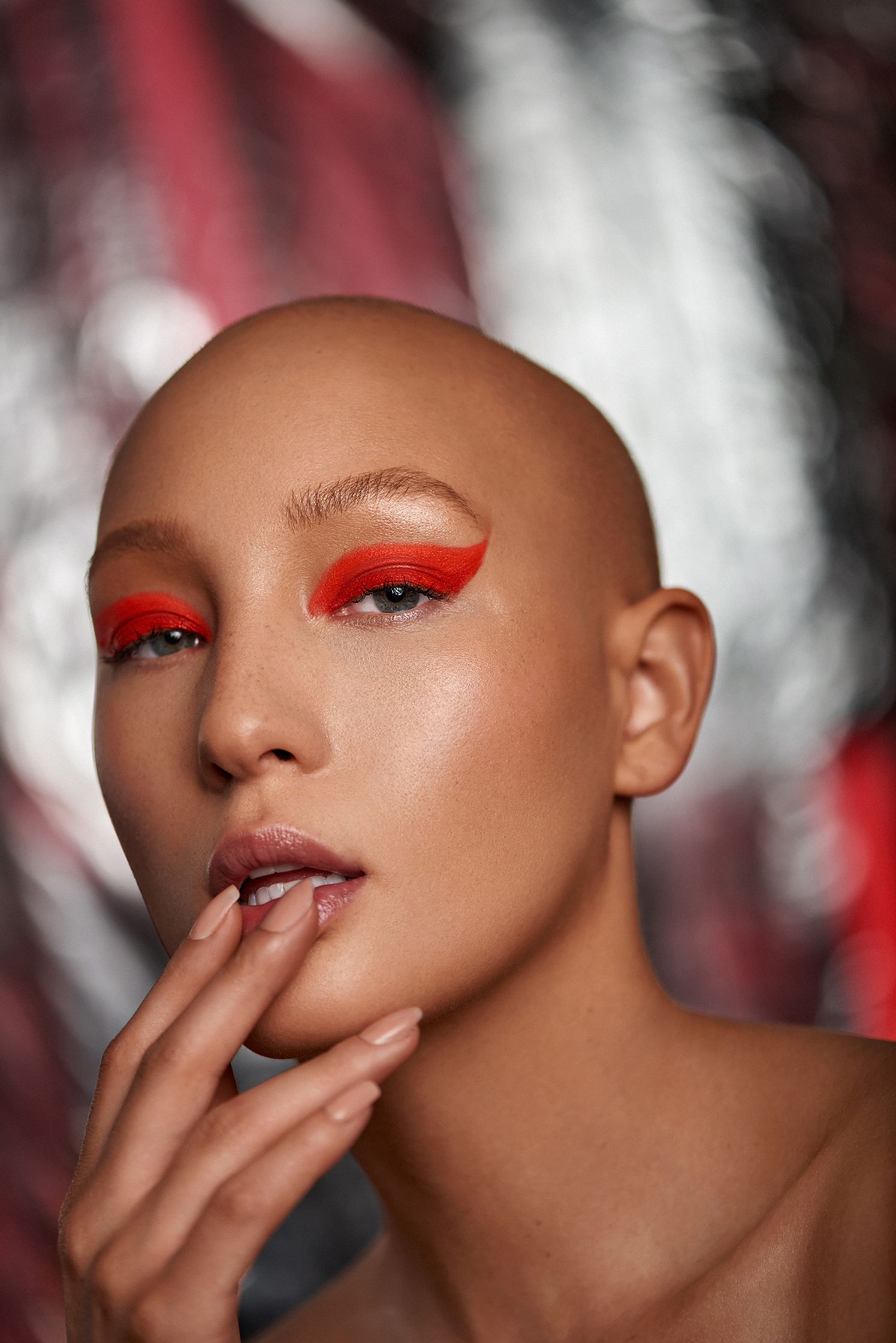 a woman with a bald head and red eye makeup