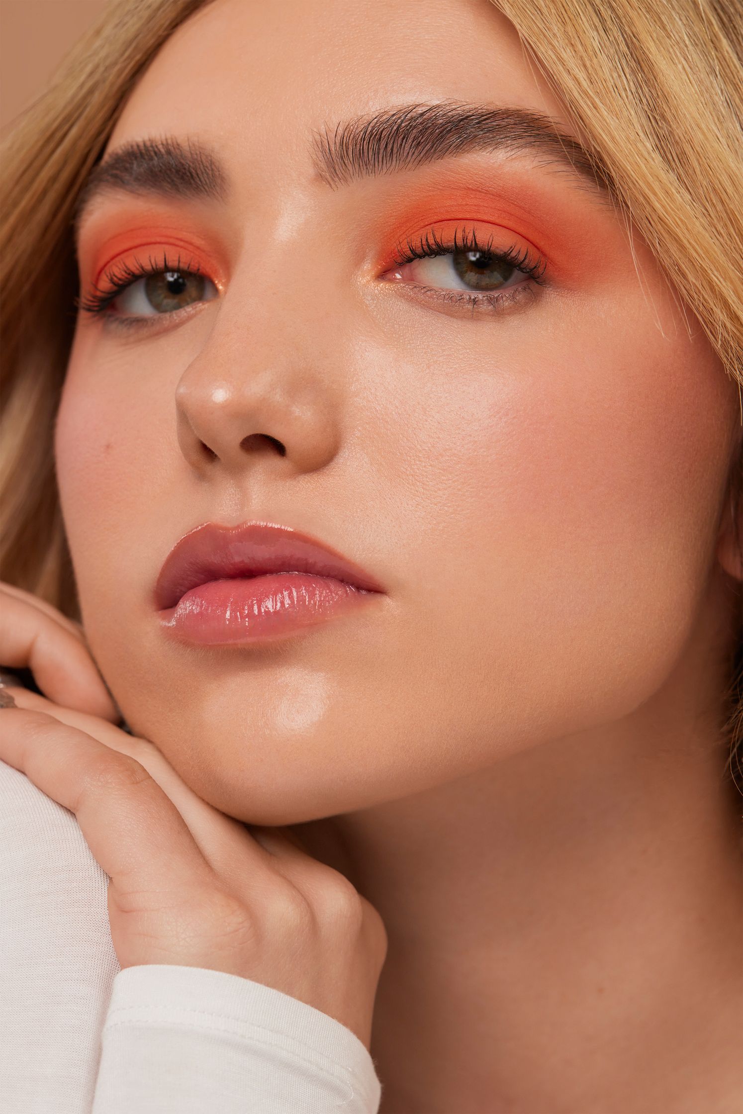 a woman wearing orange eyeshadow and a white shirt