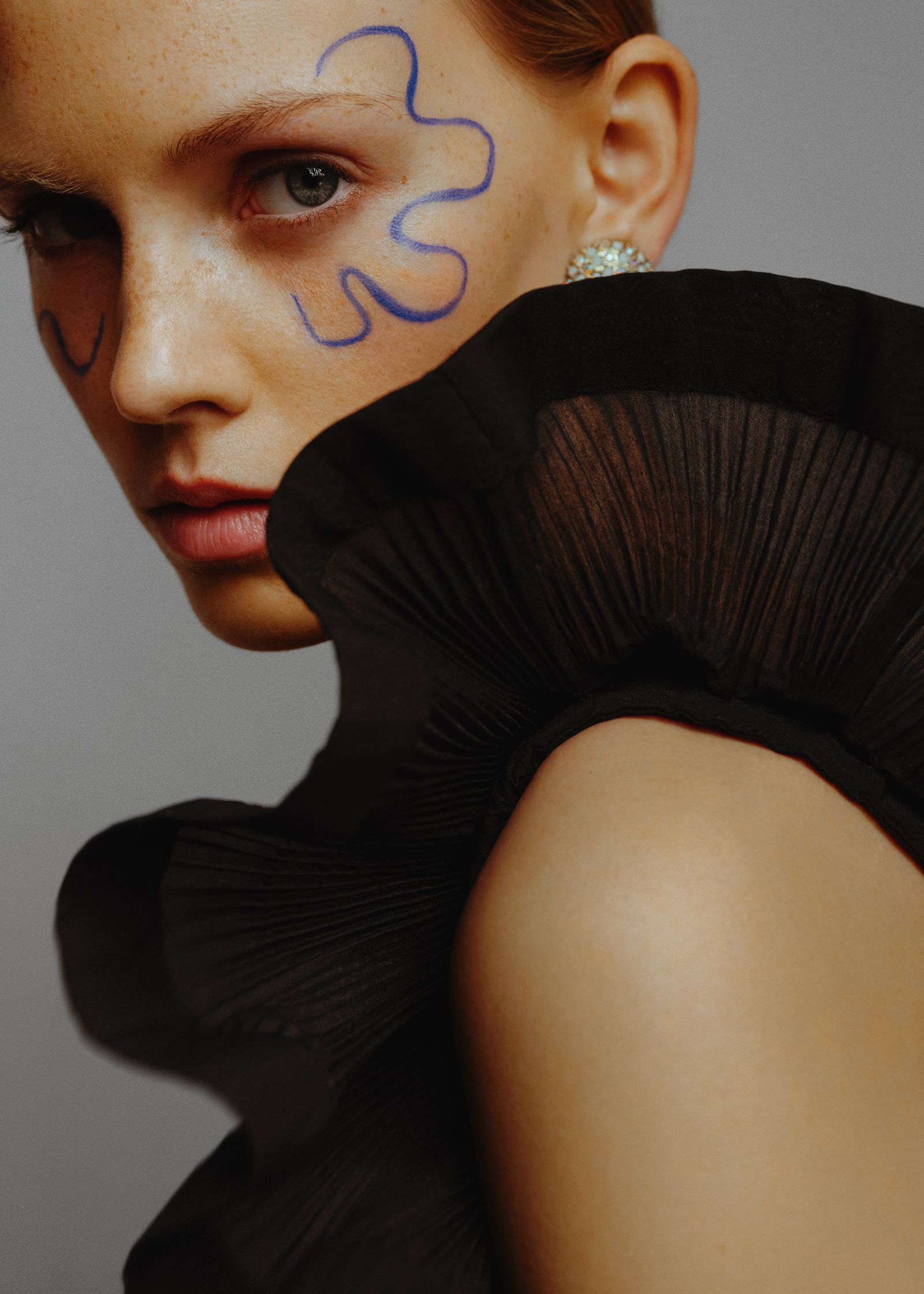 a woman wearing a black dress with blue paint on her face