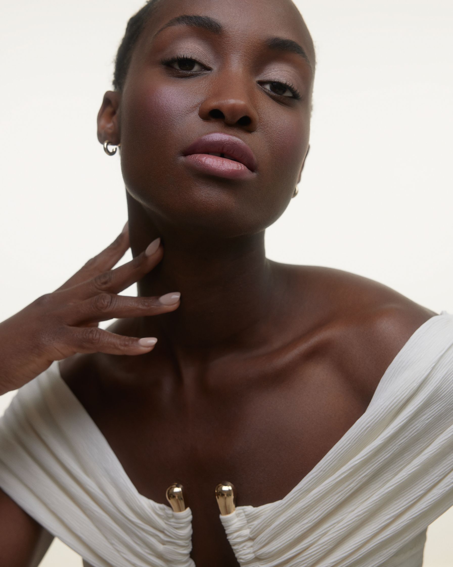a black woman in a white dress posing with her hand on her chin