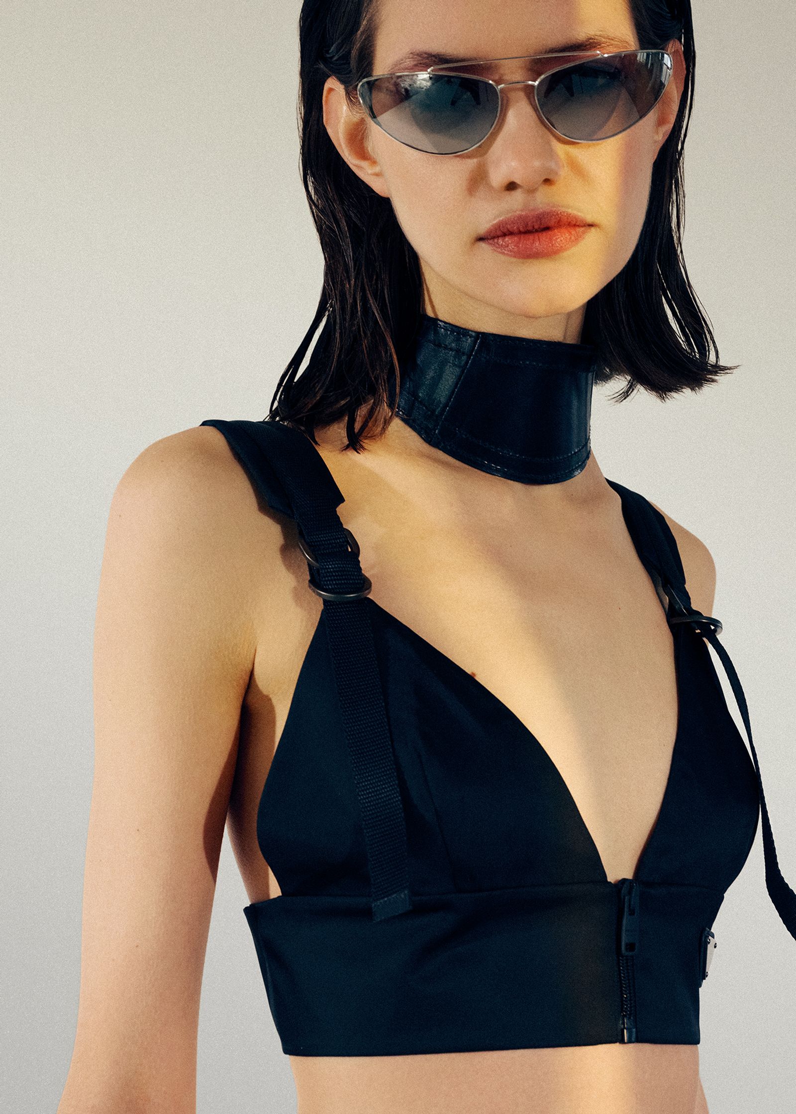 a model wearing a black bra top and sunglasses