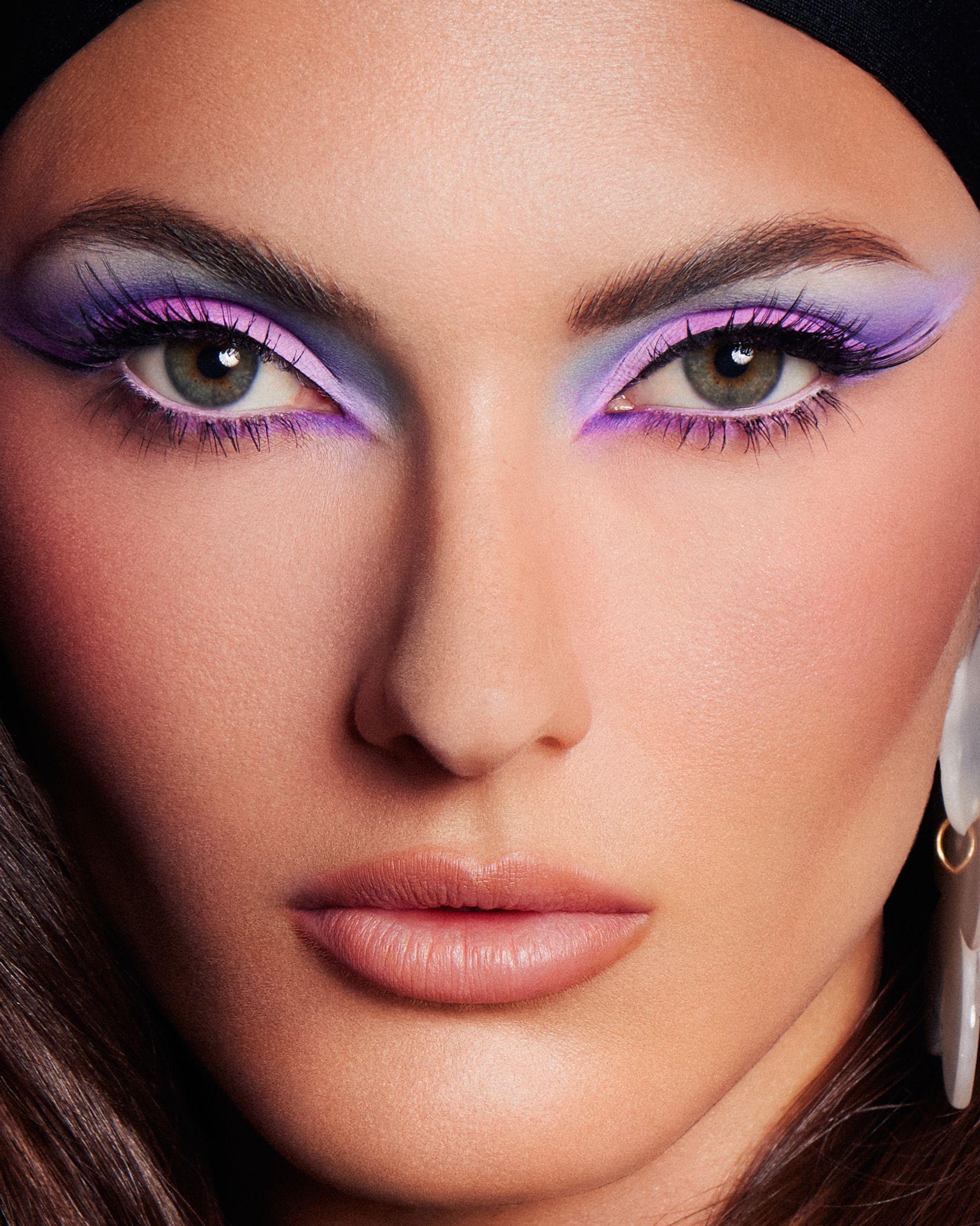 a woman with purple eye makeup and a black hat