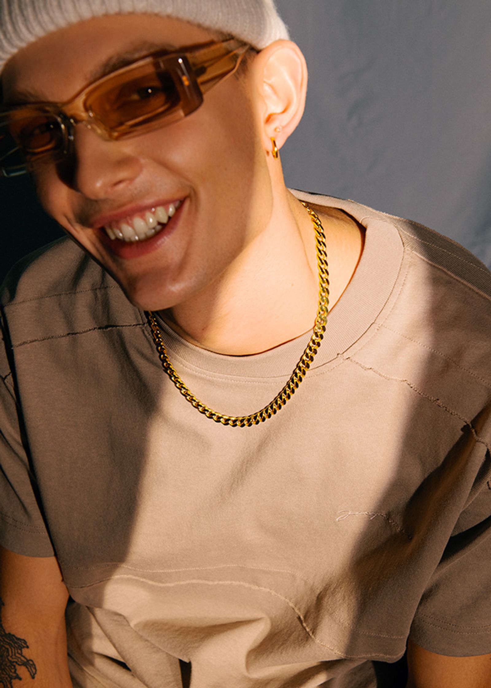 a man wearing sunglasses and a beanie smiles