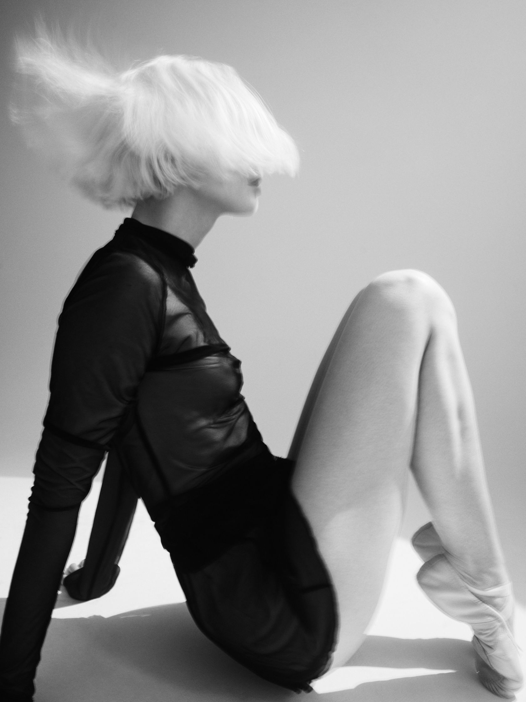 a black and white photo of a woman sitting on the floor