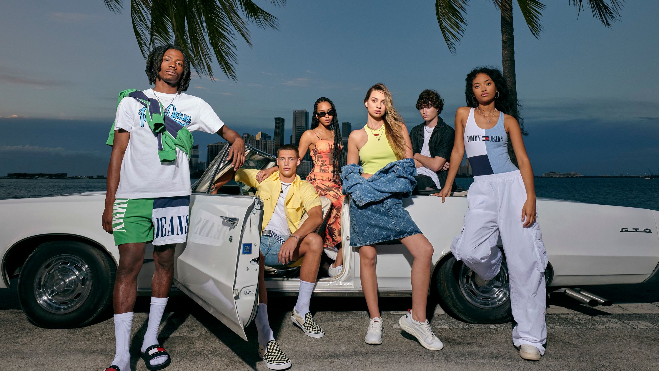 a group of young people posing in front of a car use uk
