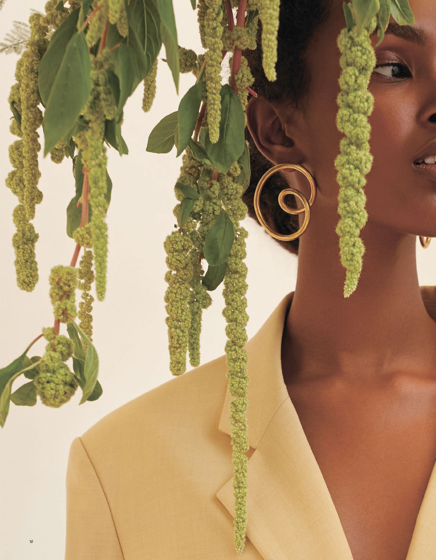 a woman in a yellow suit is posing in front of a plant