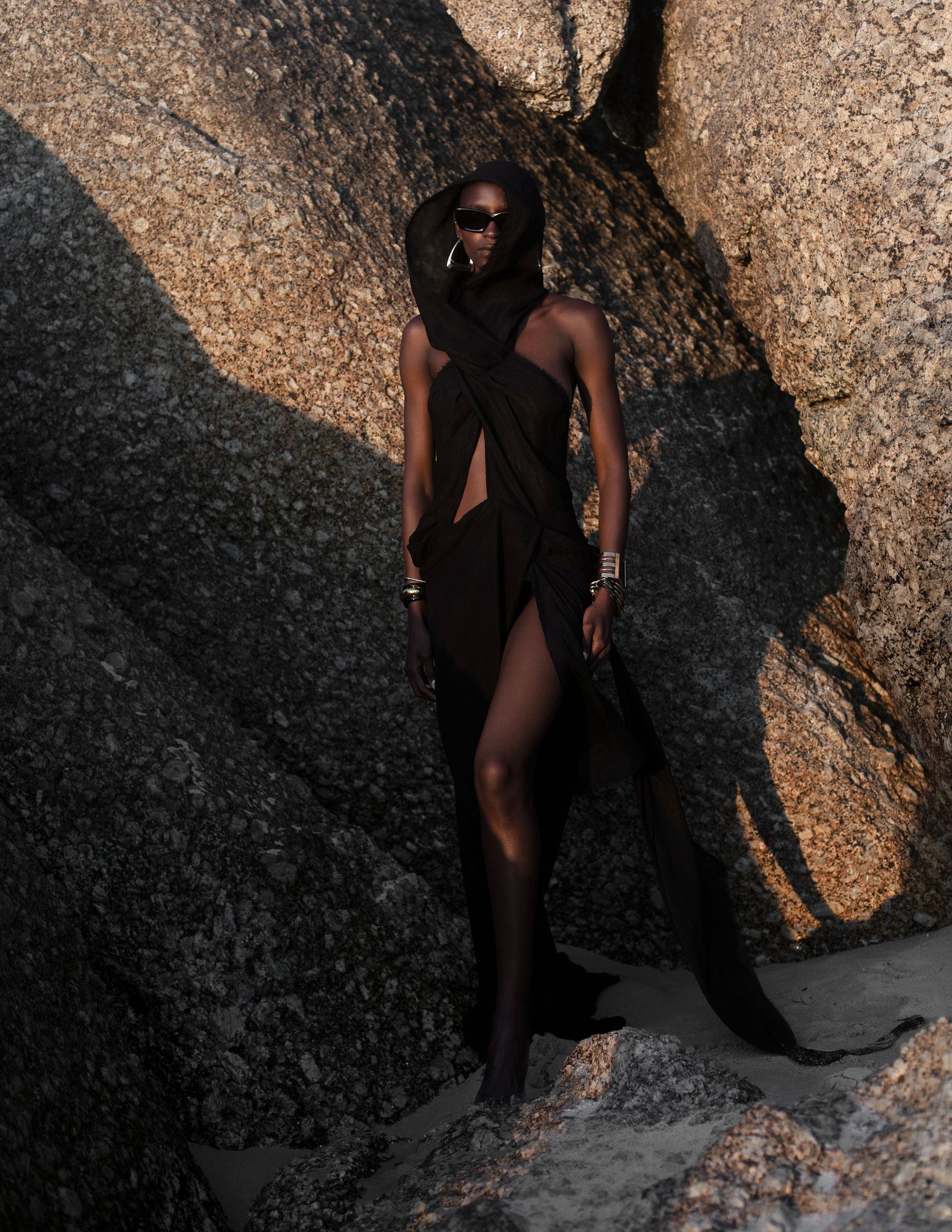 a woman in a black dress standing on rocks