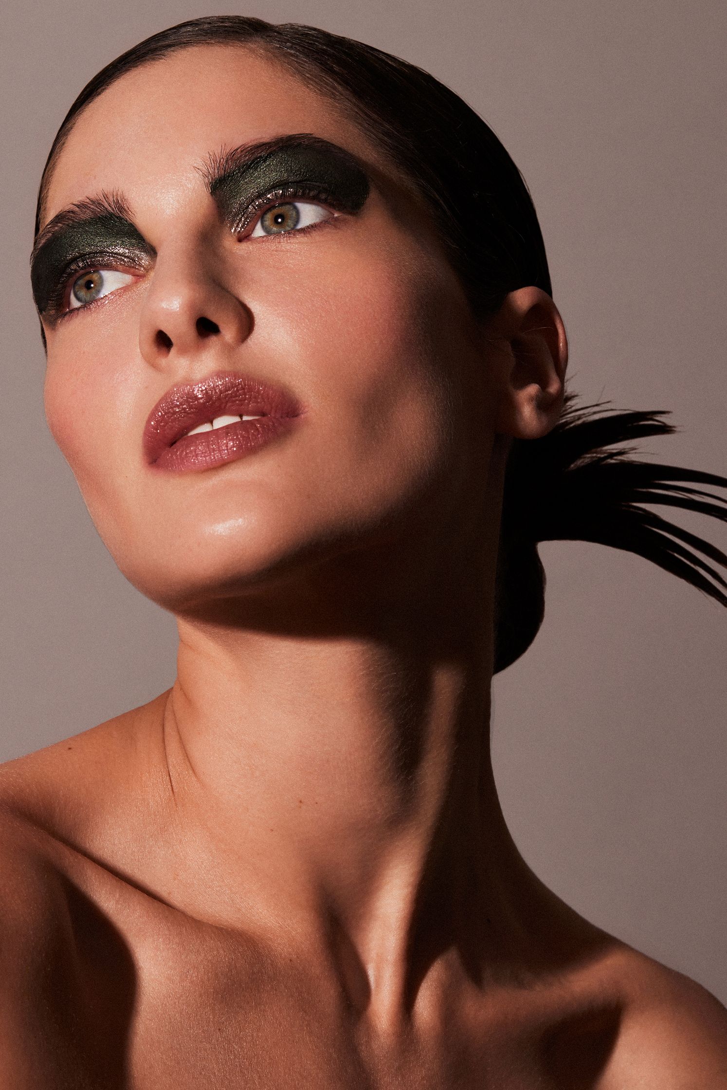 a woman with green eye makeup and feathers
