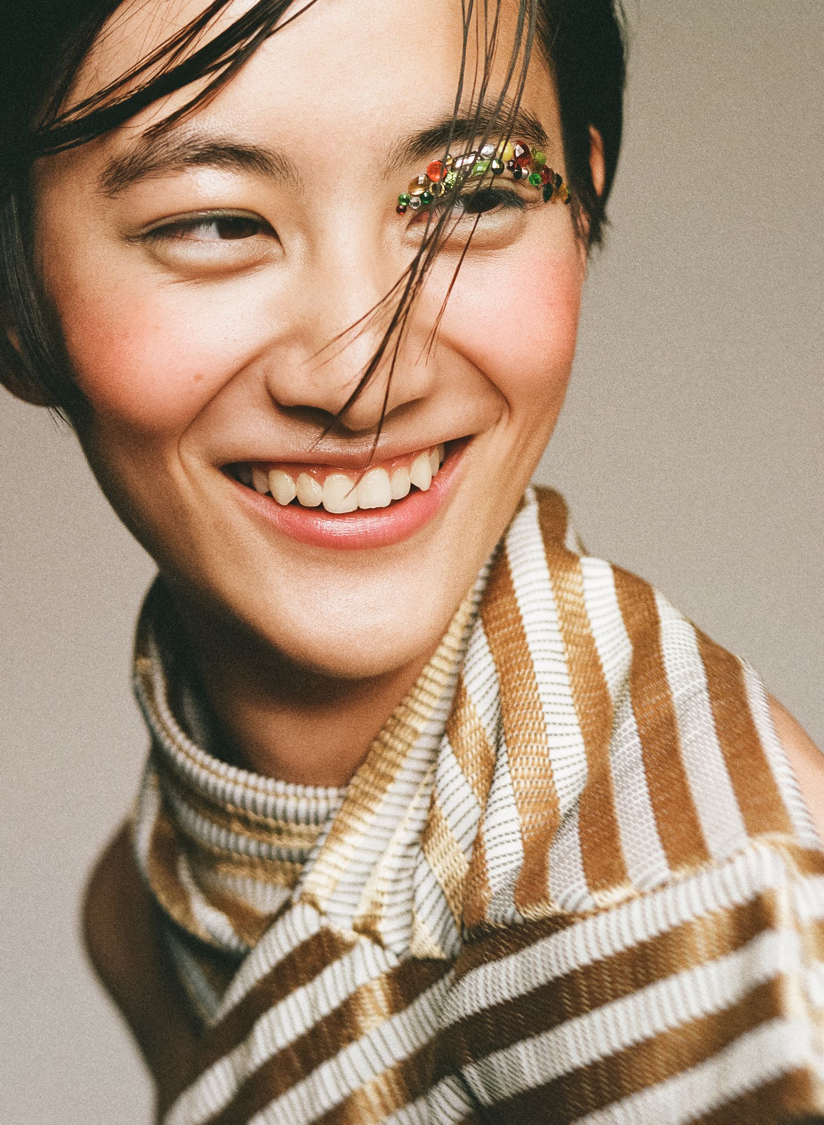 a woman wearing a striped scarf smiles for the camera