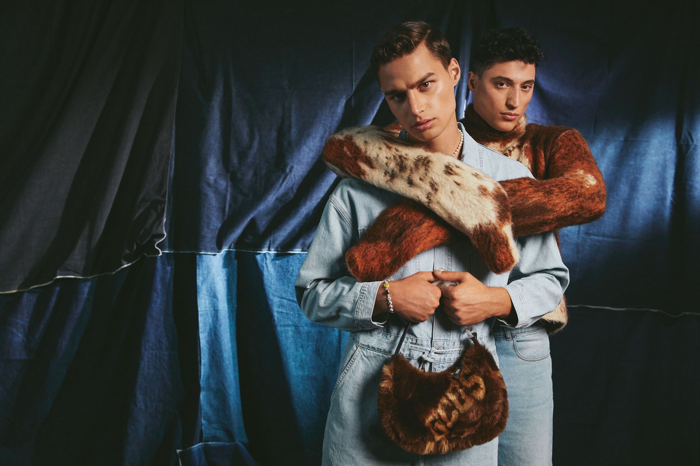 two men posing in front of a blue curtain