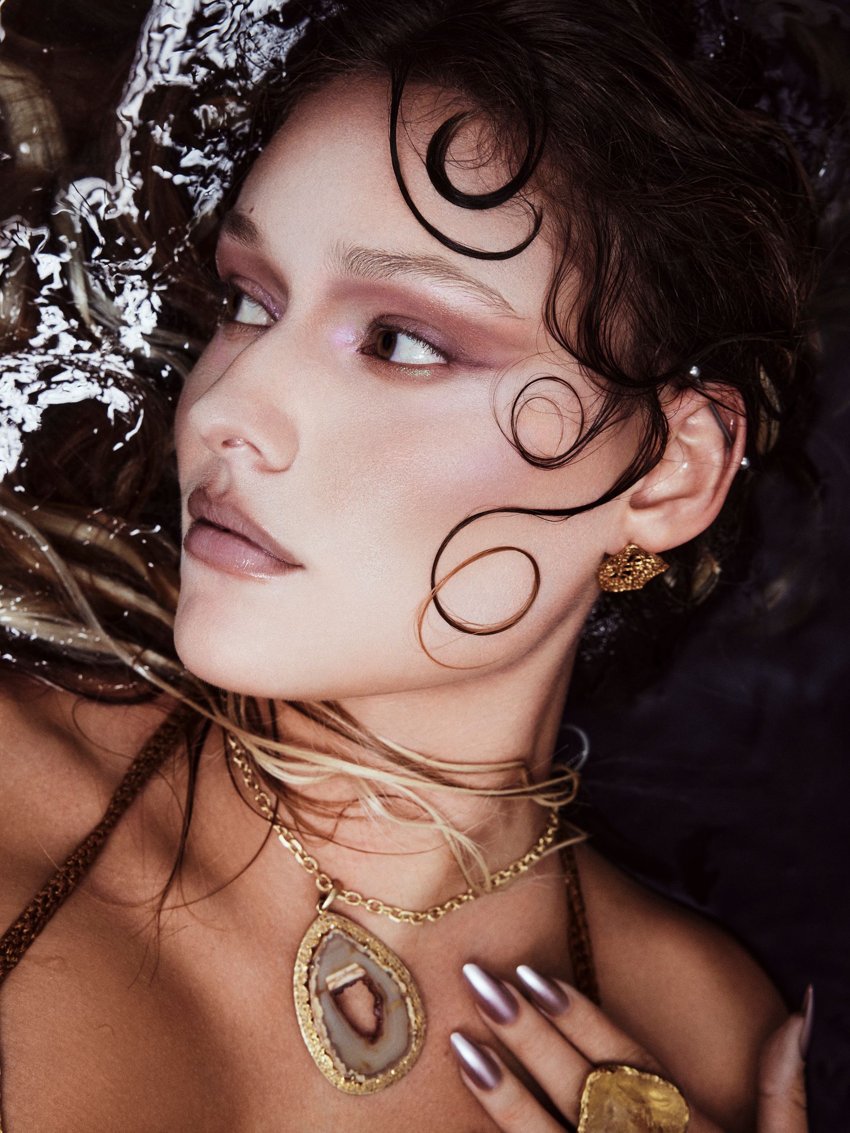 a woman posing in water with gold jewelry