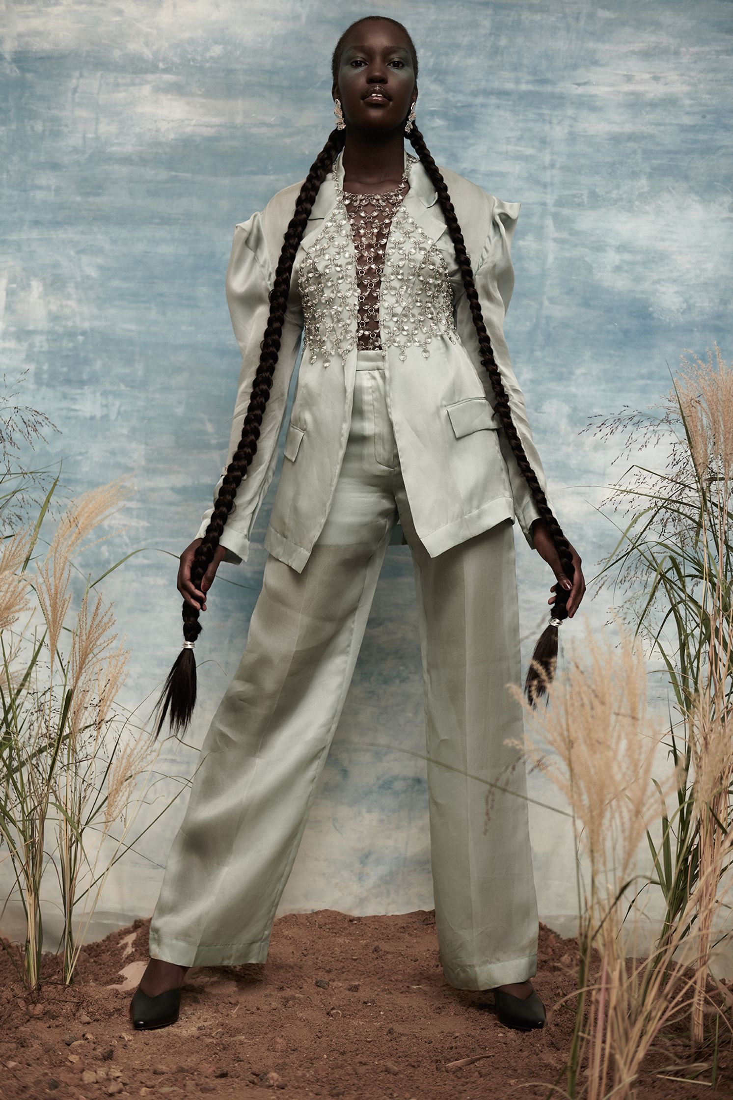 a black woman in a white suit posing in front of a field