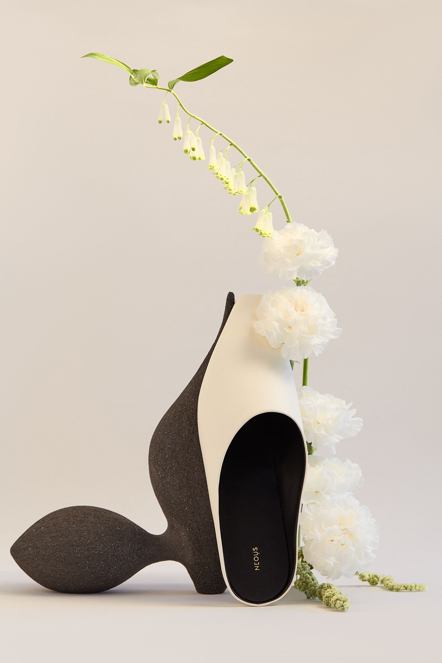 a pair of black and white shoes next to a white flower