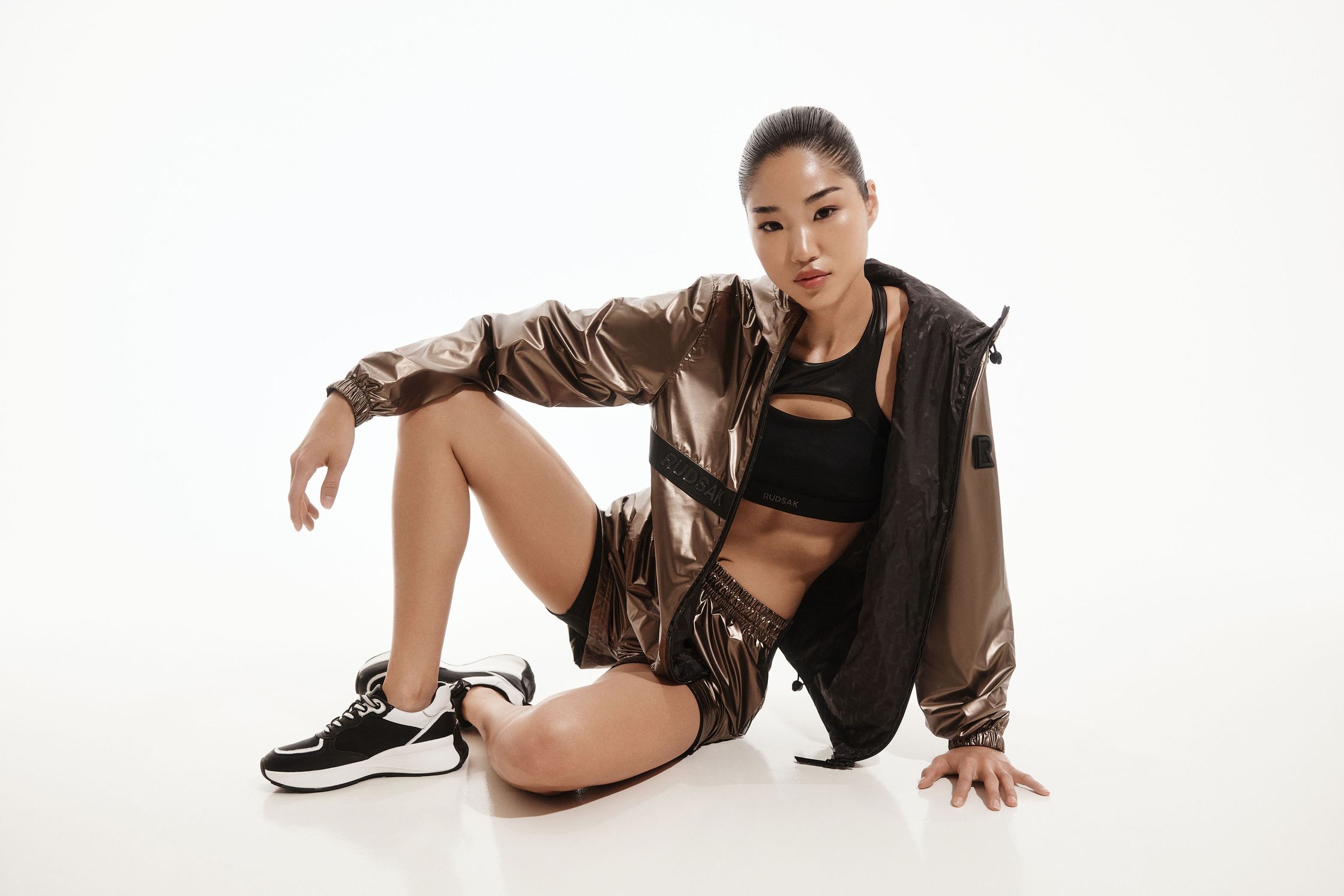 a woman in a metallic tracksuit posing on the floor
