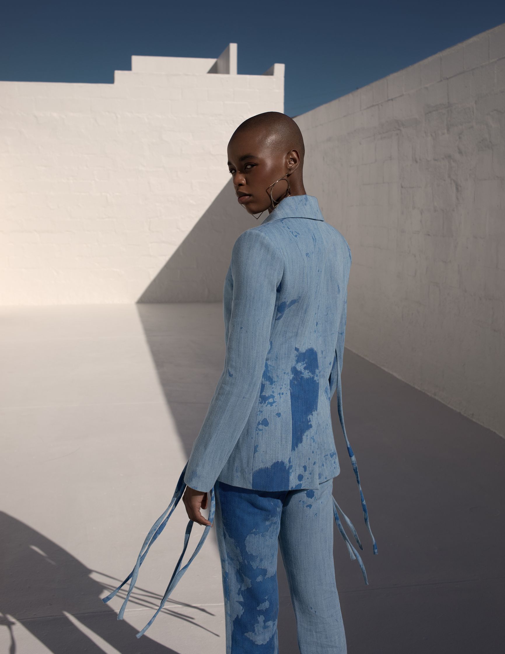 a black man in a blue suit standing in front of a white wall