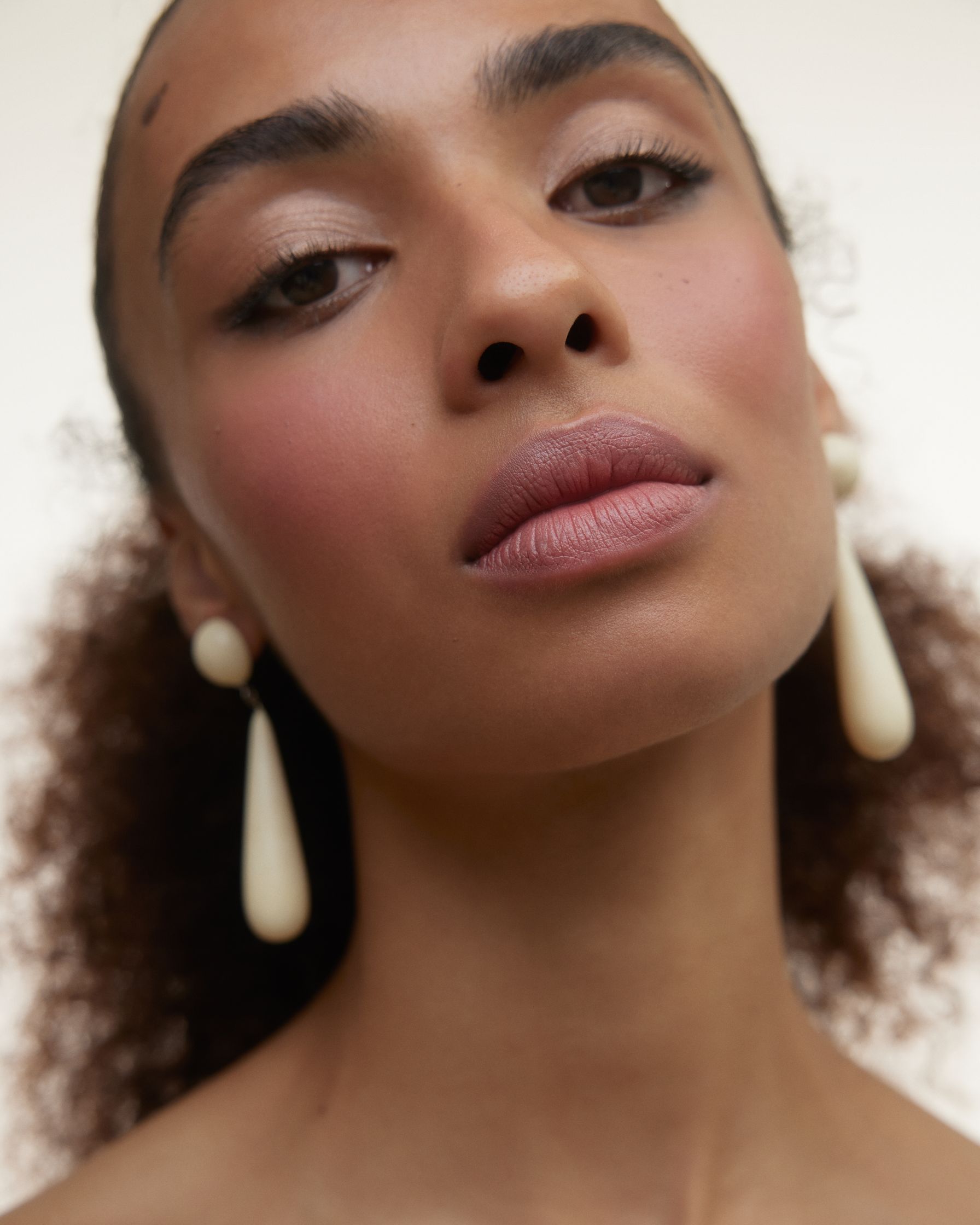 a woman with curly hair wearing a pair of earrings