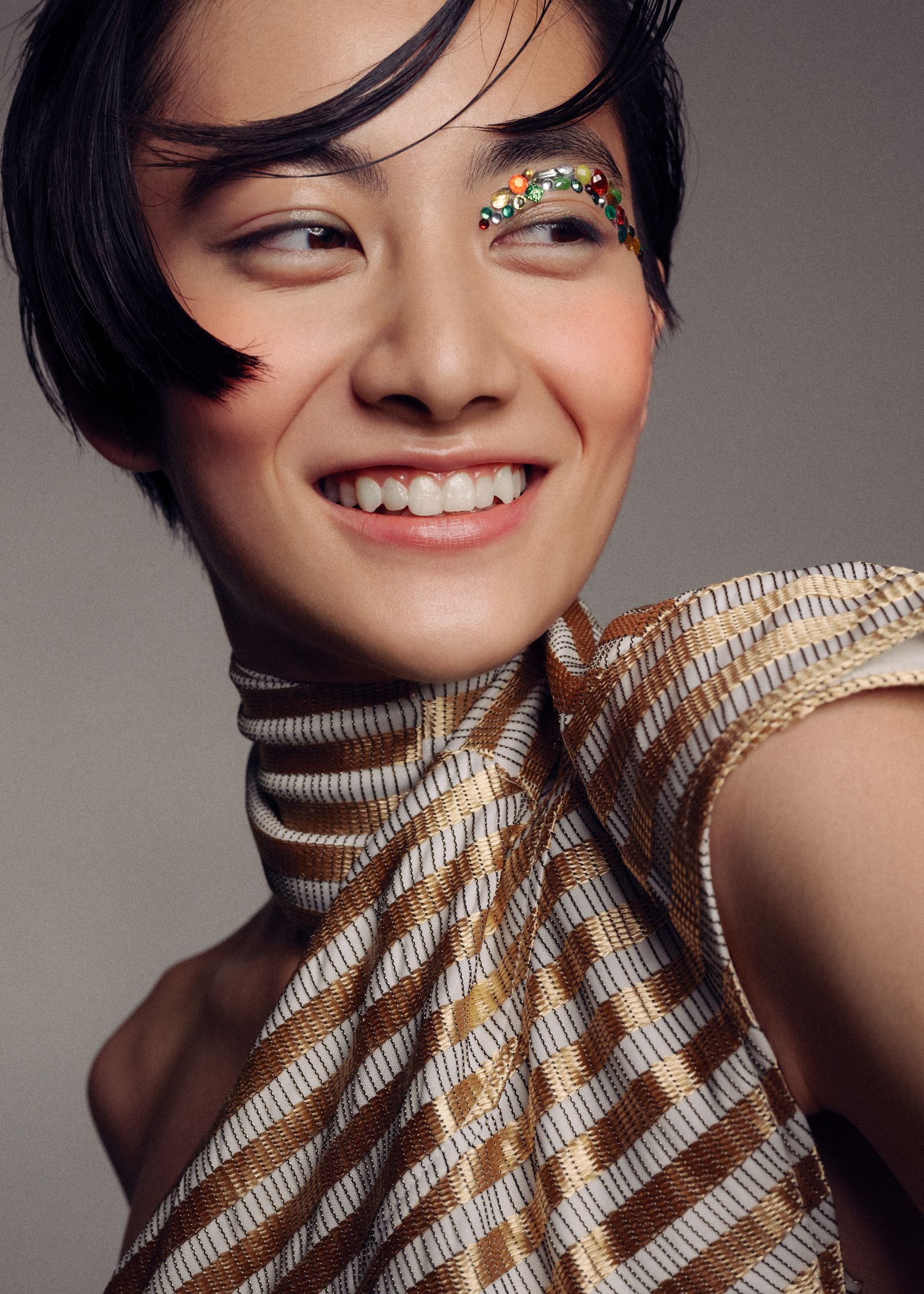 a woman wearing a gold striped dress and gold eye makeup