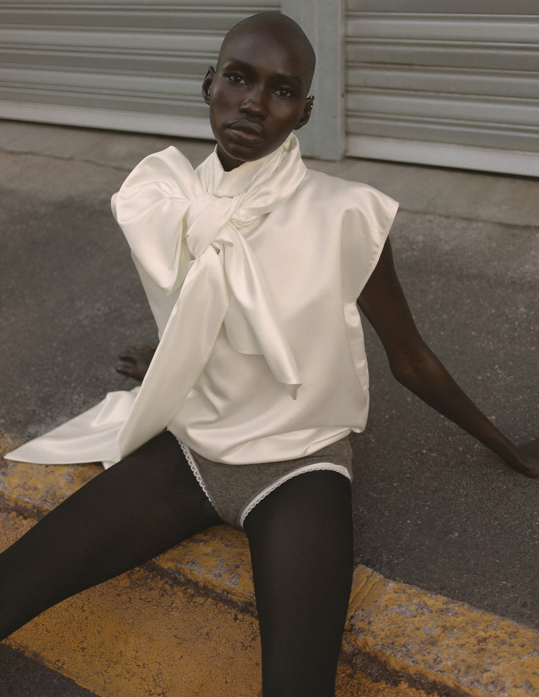 a woman in a white top and black shorts sitting on a curb