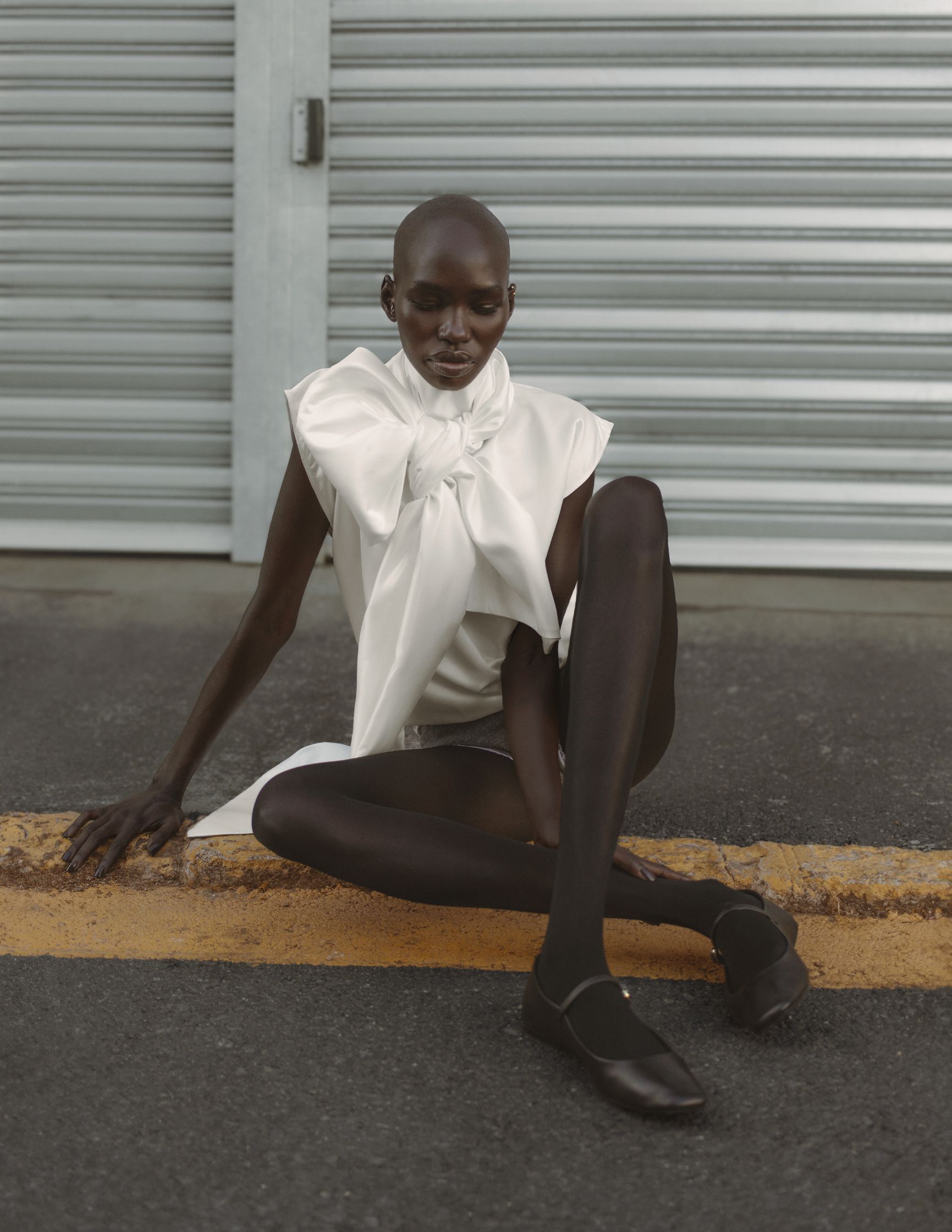 a black woman in a white dress sitting on the ground