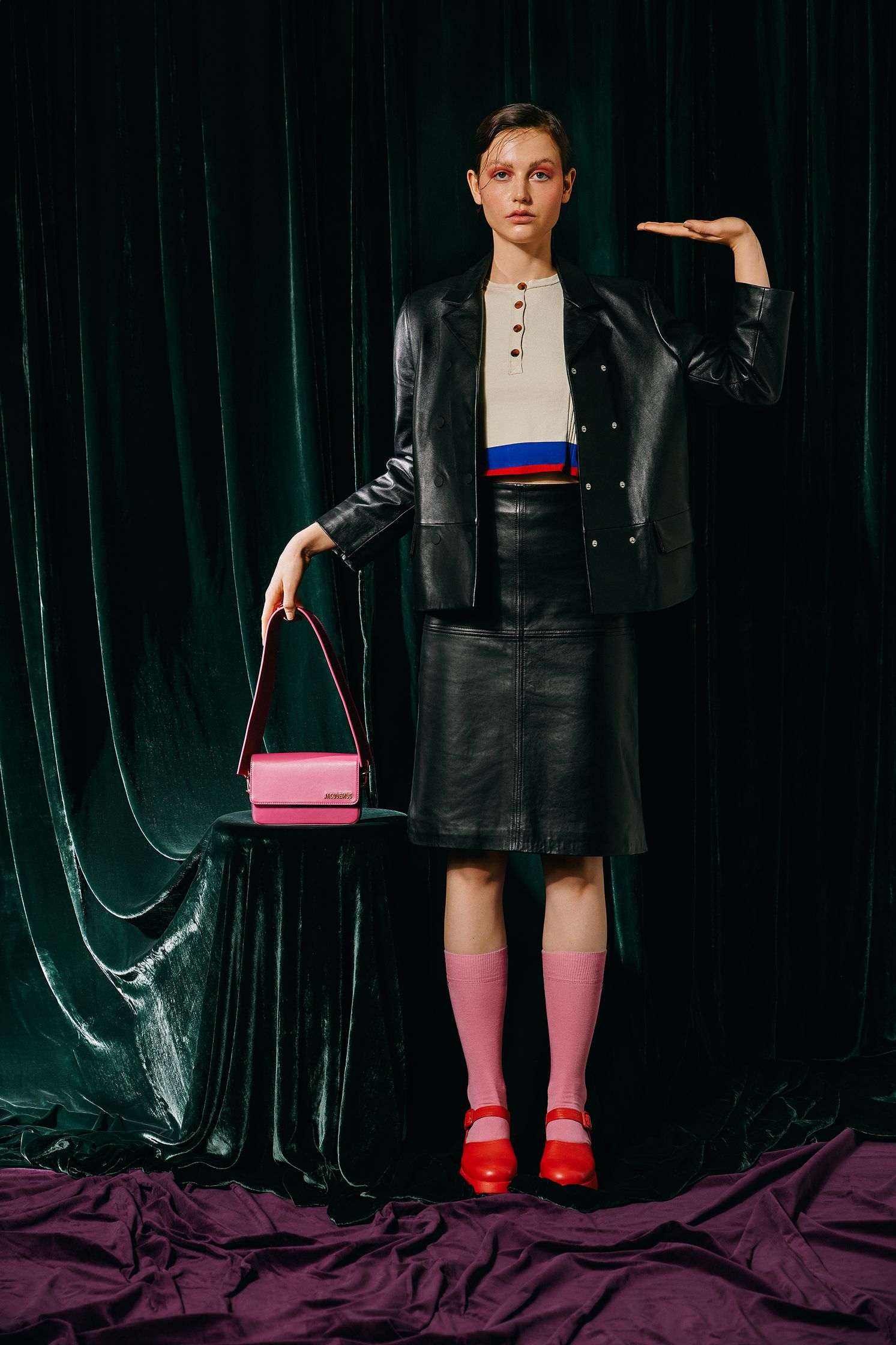 a woman in a black jacket and skirt holding a pink purse