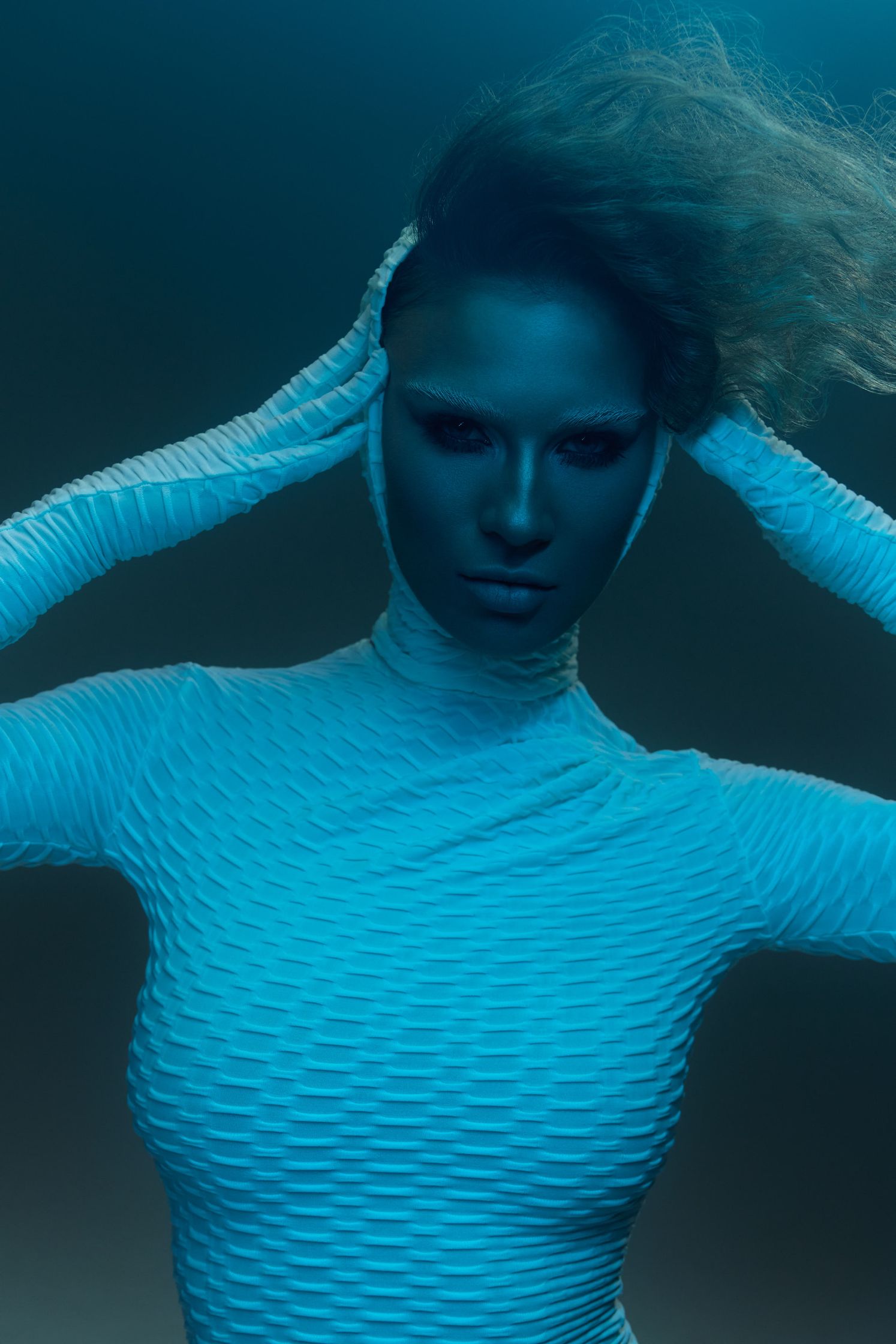 a woman in a blue bodysuit posing for a photo shoot