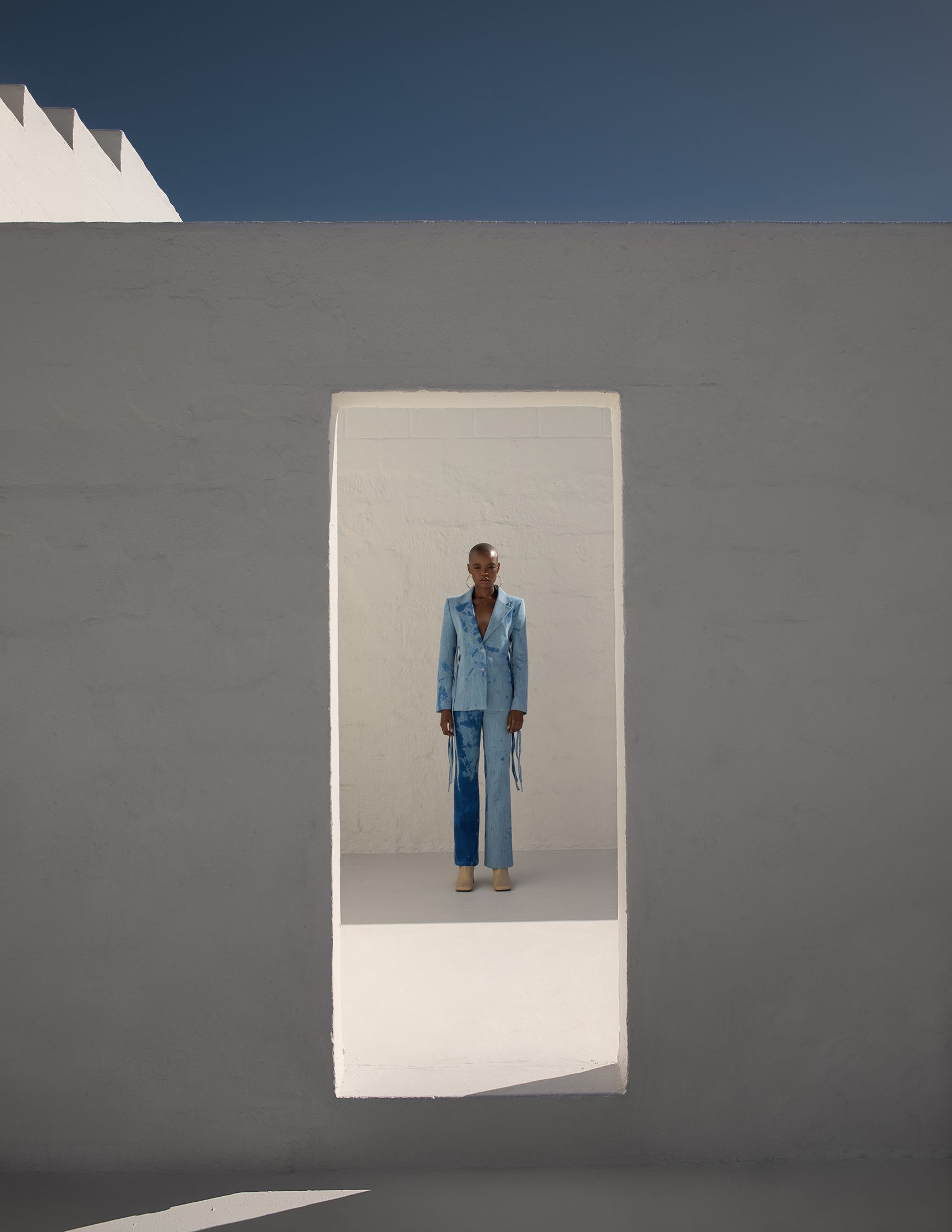 a man in a blue suit standing in a white room