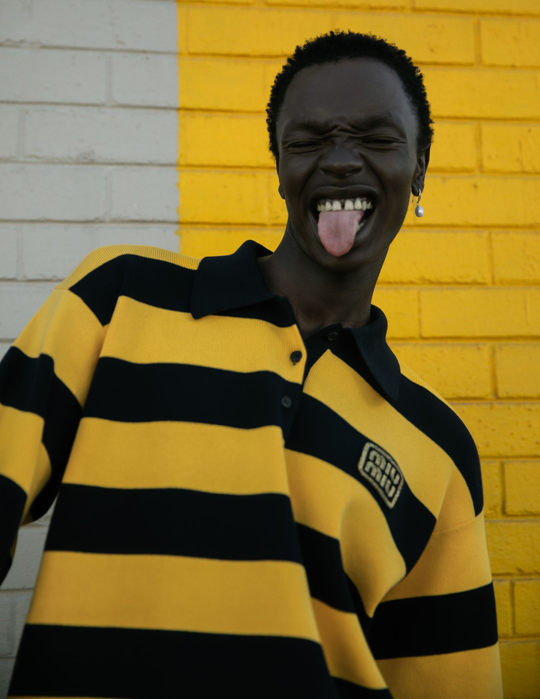 a man in a yellow and black striped shirt is sticking his tongue out