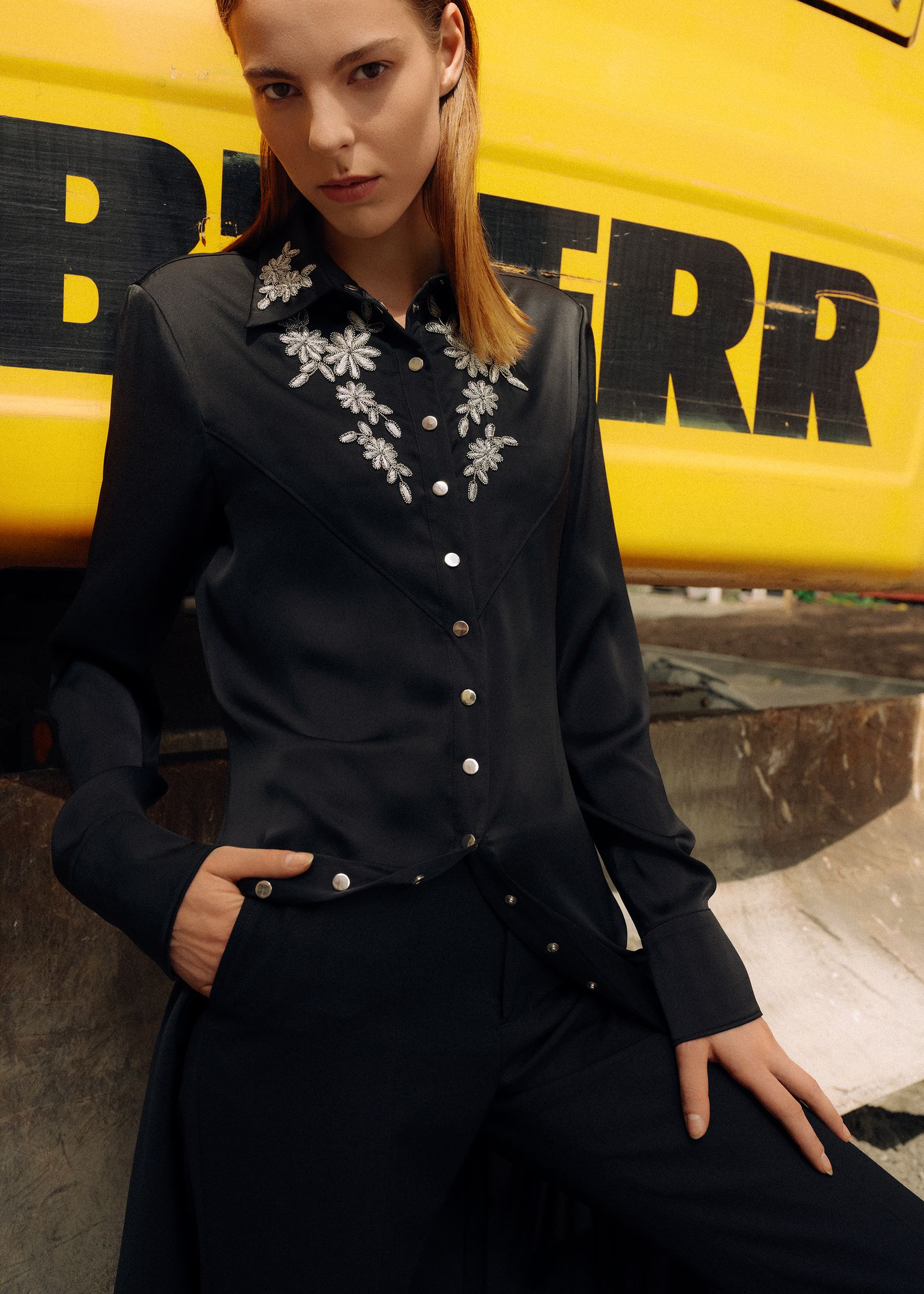 a woman is posing in front of a yellow truck