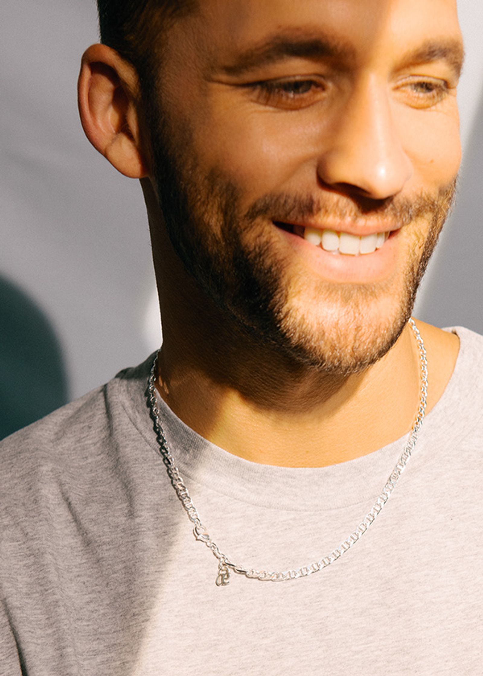 a man with a beard wearing a silver chain necklace