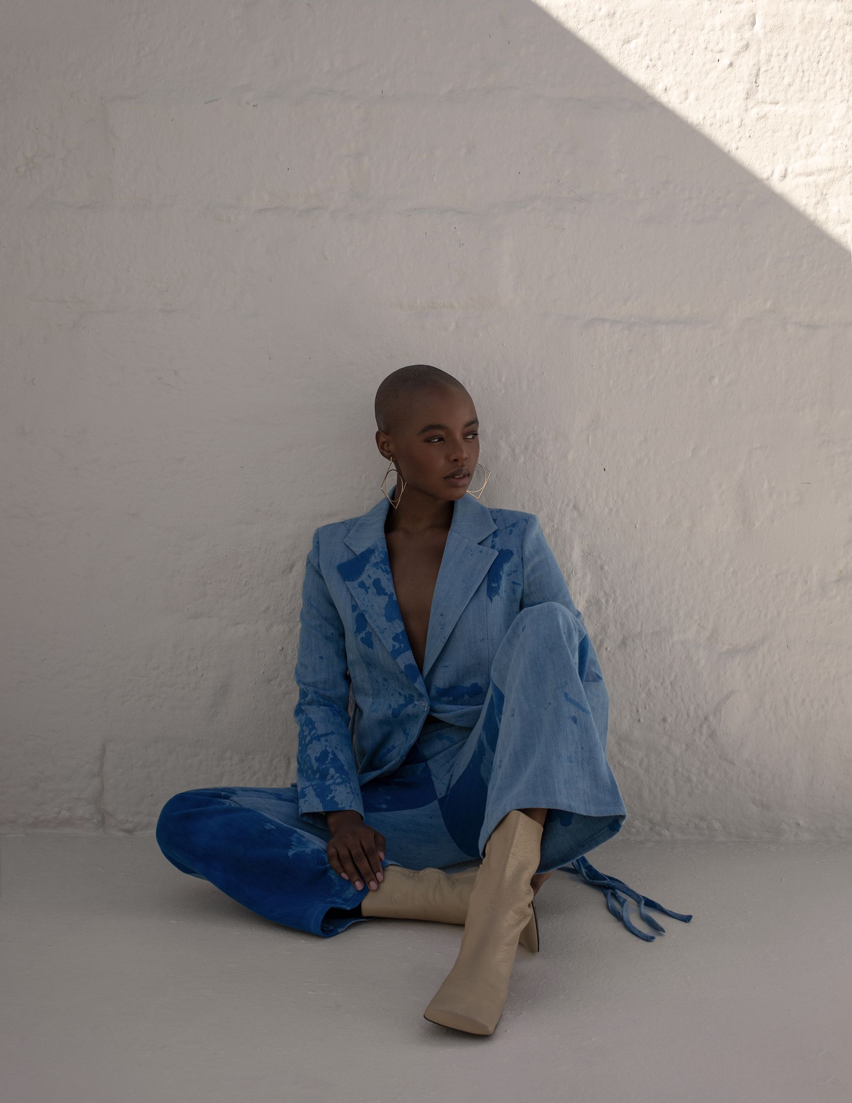 a woman in a blue suit sitting on a white wall