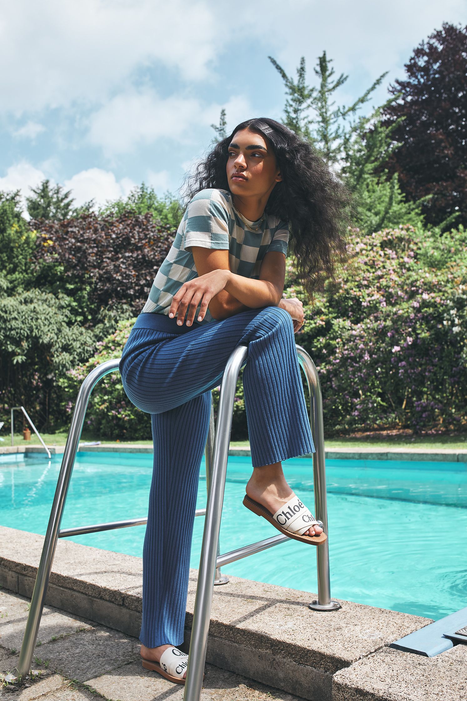 a woman leaning on a railing next to a pool