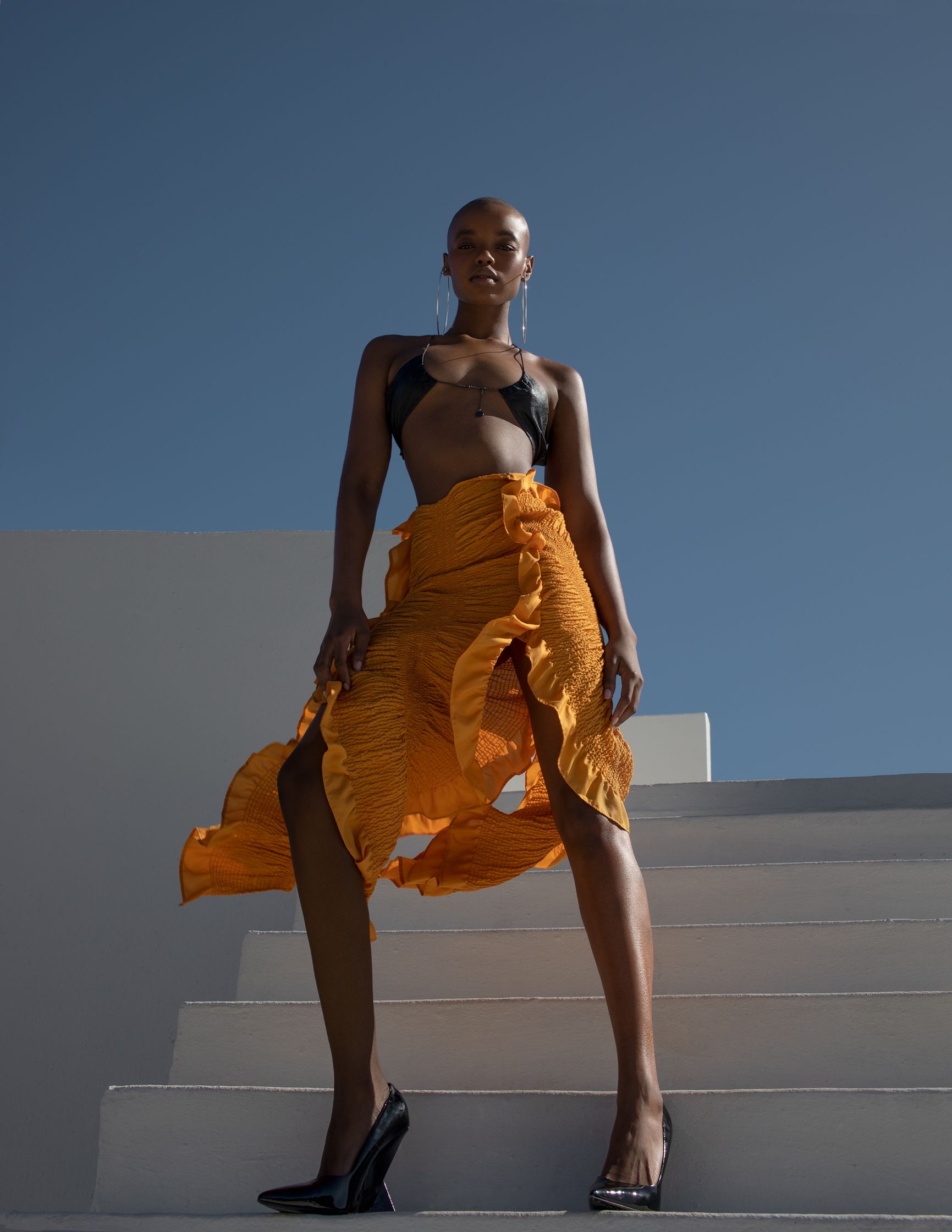 a woman in an orange skirt posing on a set of stairs
