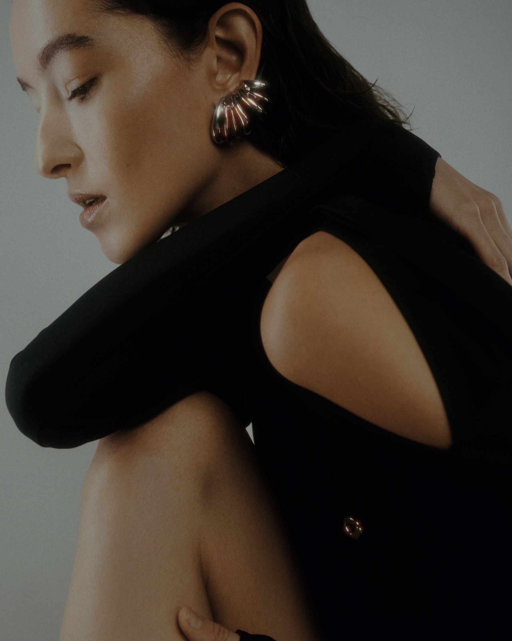 a woman wearing a black top and earrings