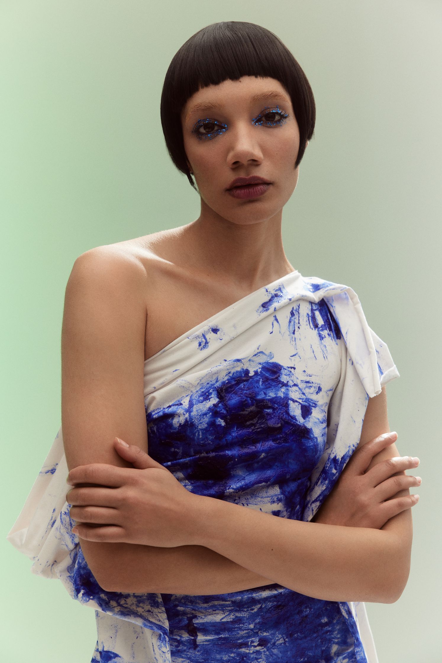 a woman in a blue dress posing with her arms crossed